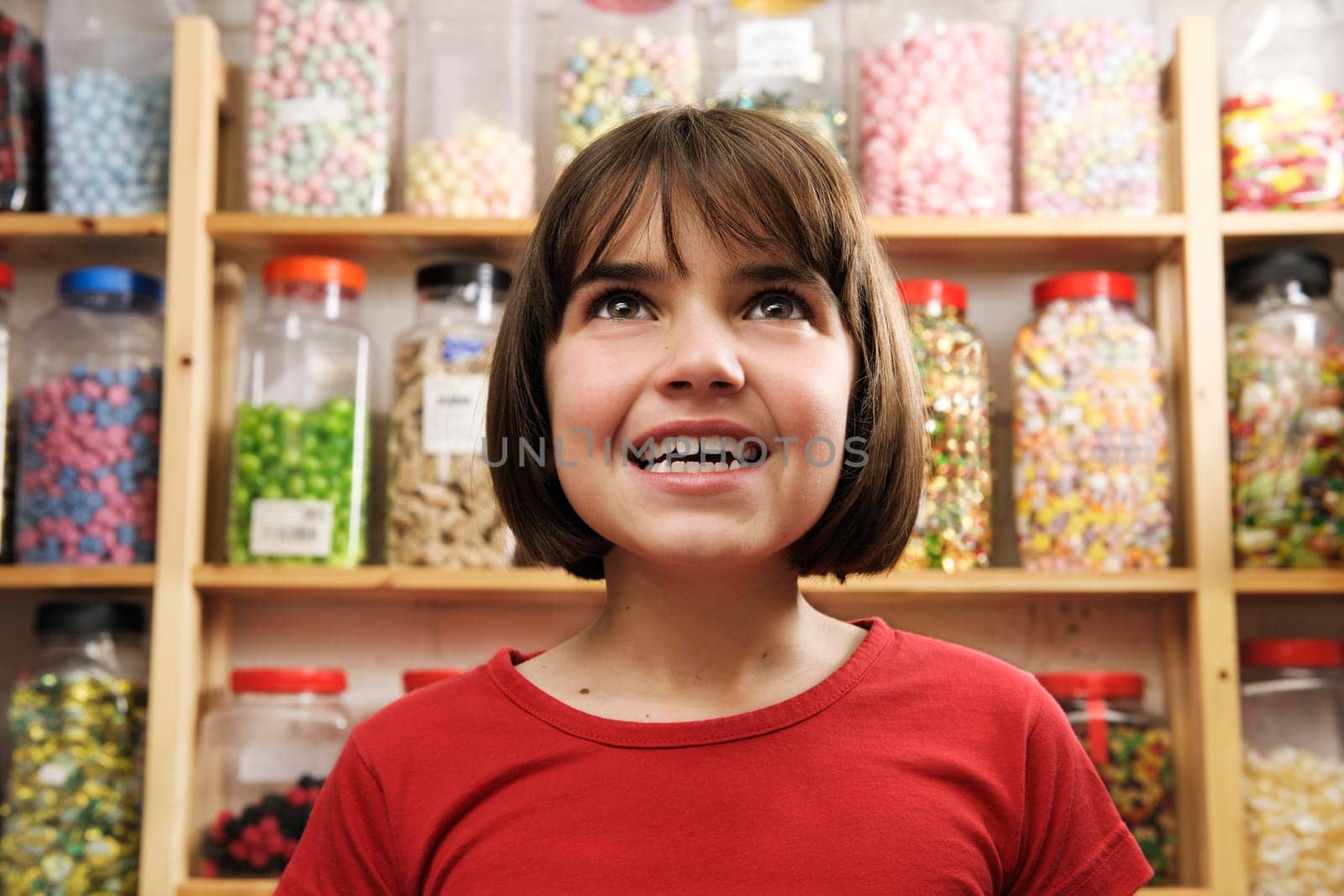 young girl looking at rows of sweets in shop