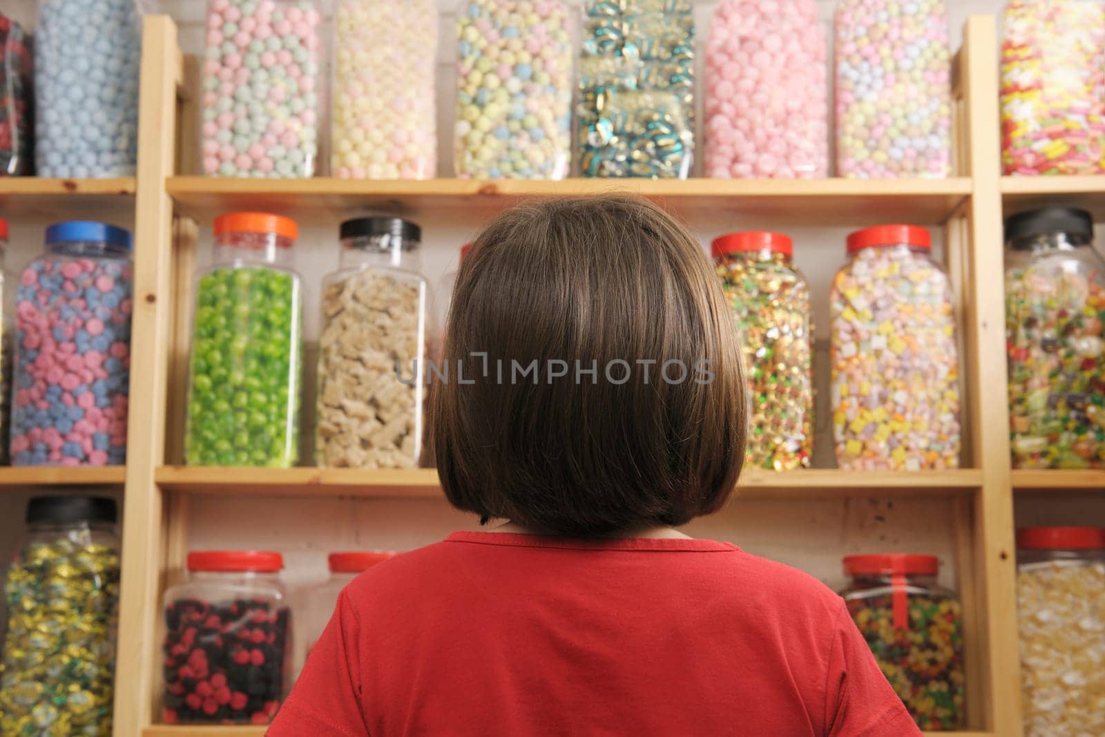 young girl looking at rows of sweets in shop