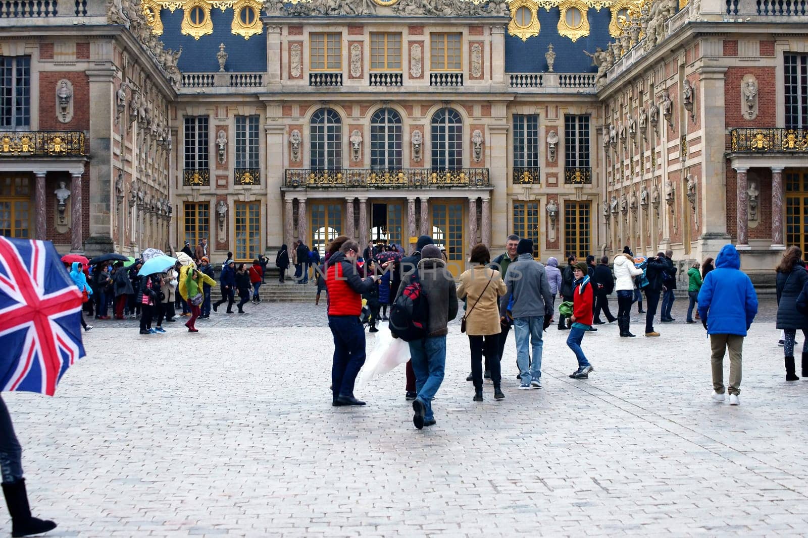 Paris,France – December 30,2013: Tourists stand and walk in rainy weather on a square of the Palace of Versailles on December 30,2013 in  Paris.