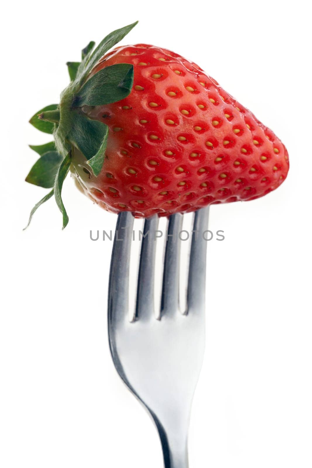 whole strawberry pierced on a fork against plain background