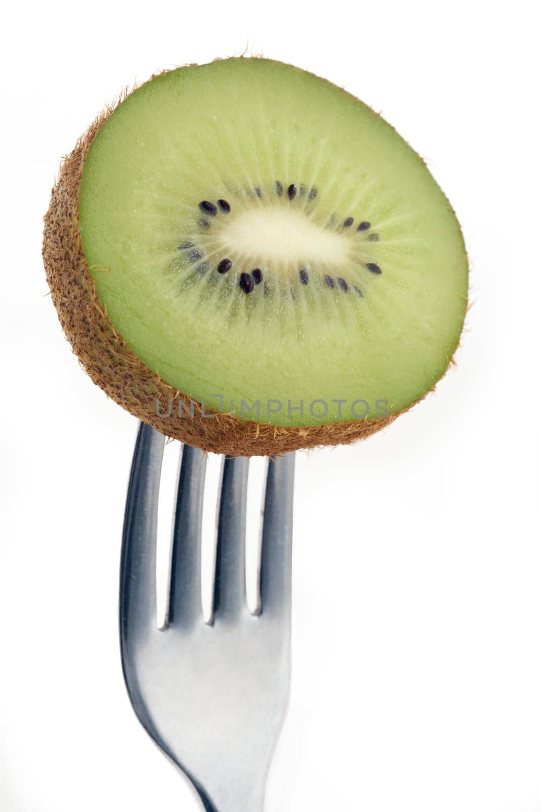 slice of kiwi pierced on a fork against plain background