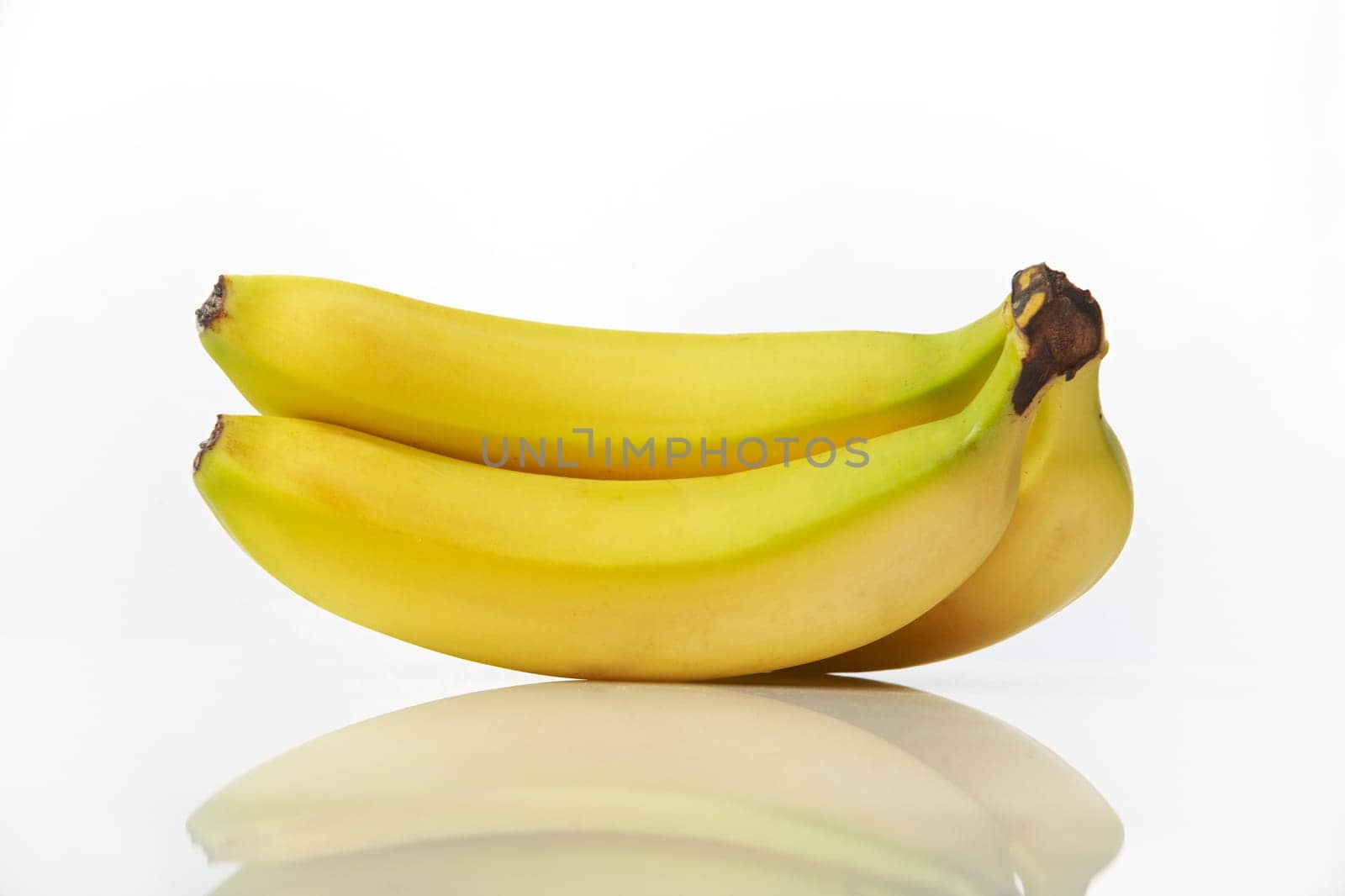 Studio shot of bunch of bananas on white background with reflection