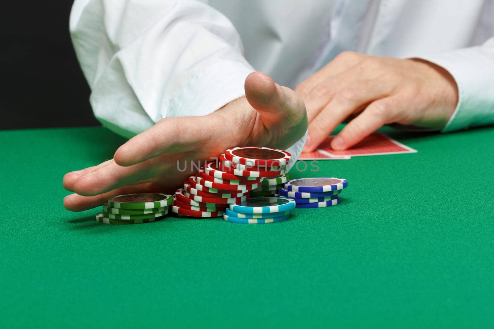 gambler. Male hand with cards and chips on green table