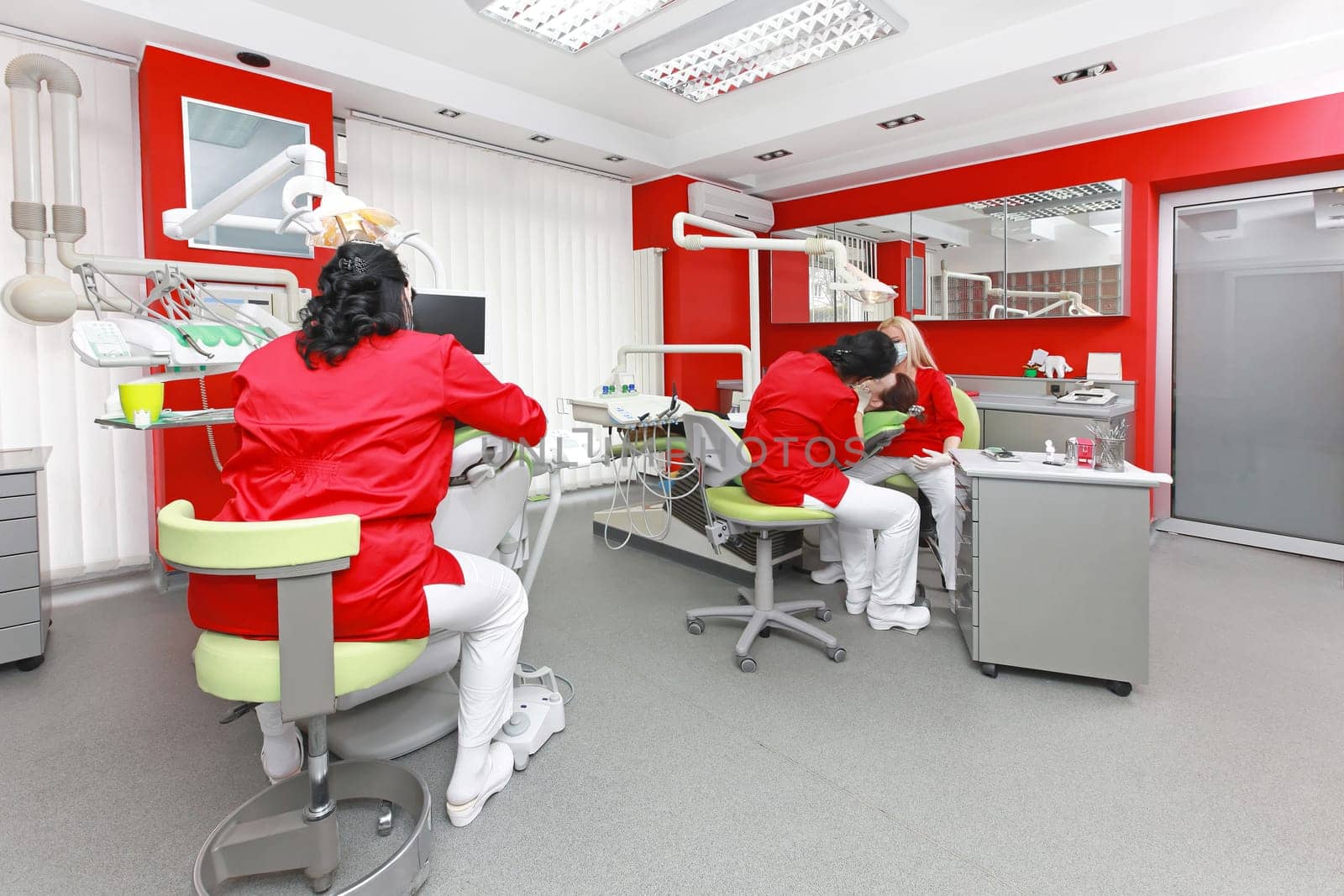 Dentists at work in modern red dental office
