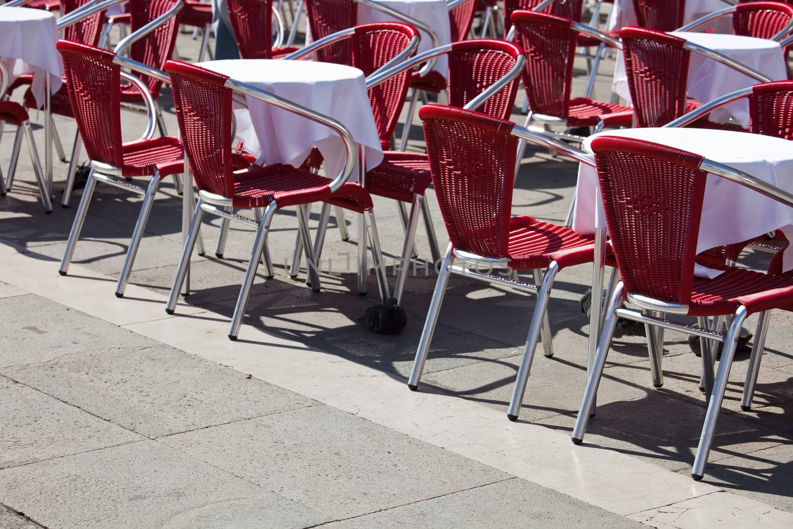 Cafe tables and chairs standing on  Saint Mark square in Venice