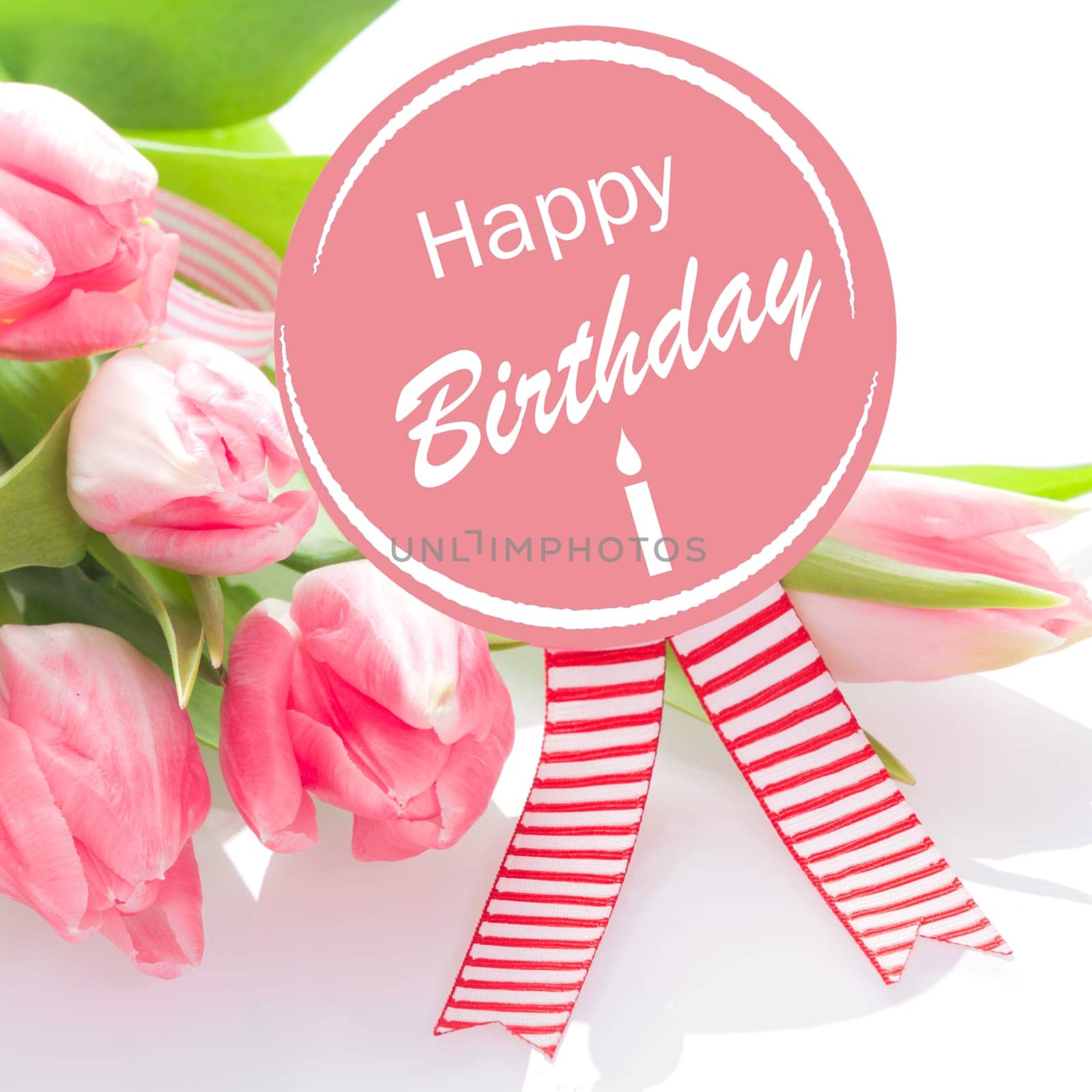 Happy Birthday wishes on a round pink rosette with colourful striped ribbons with a gift of a bouquet of natural fresh pink tulips for a loved one or sweetheart on her birthday