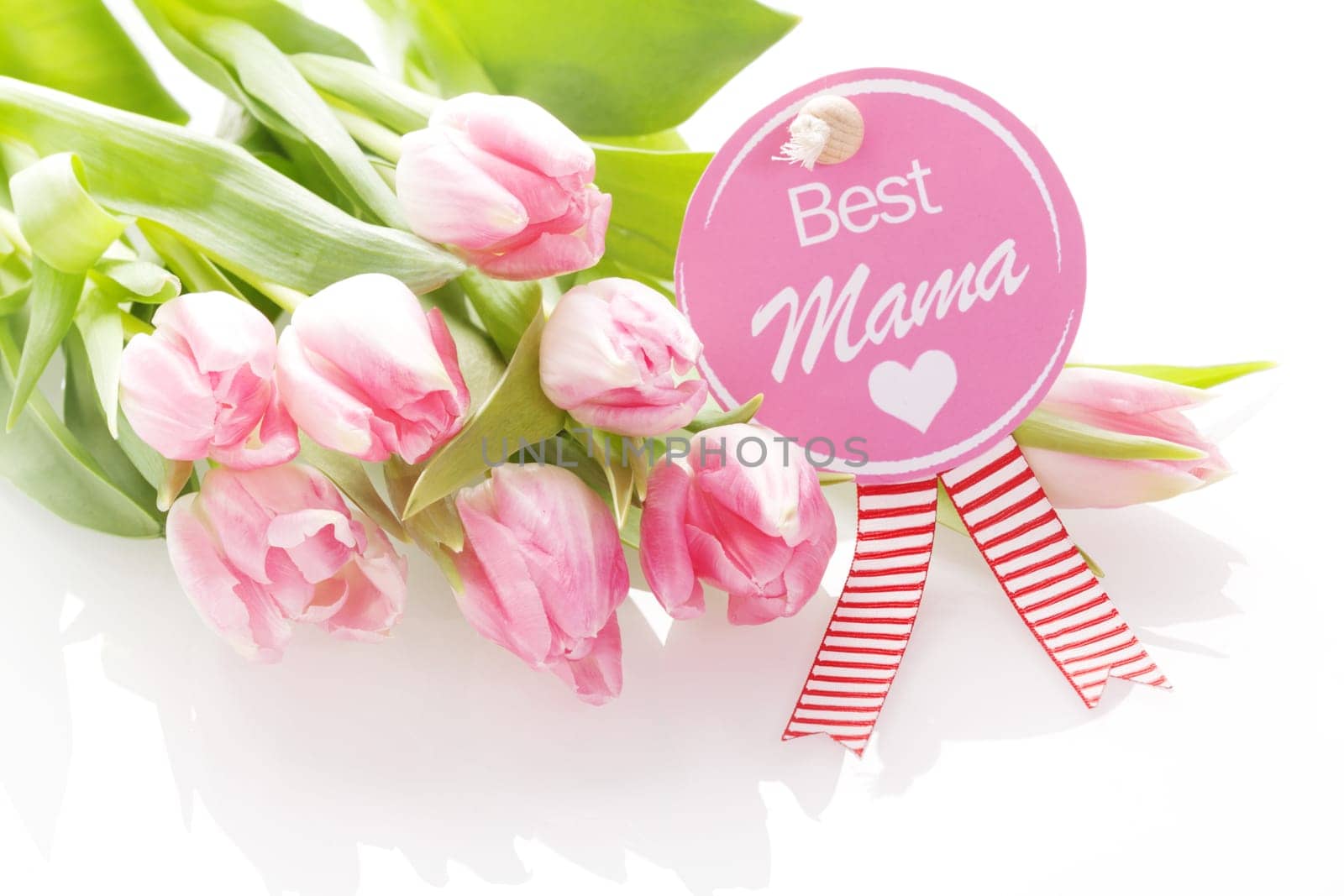 Best Mama - Mothers Day greeting on a festive circular pink rosette with the text - Best Mama - and a heart on a gift of beautiful fresh natural pink tulips