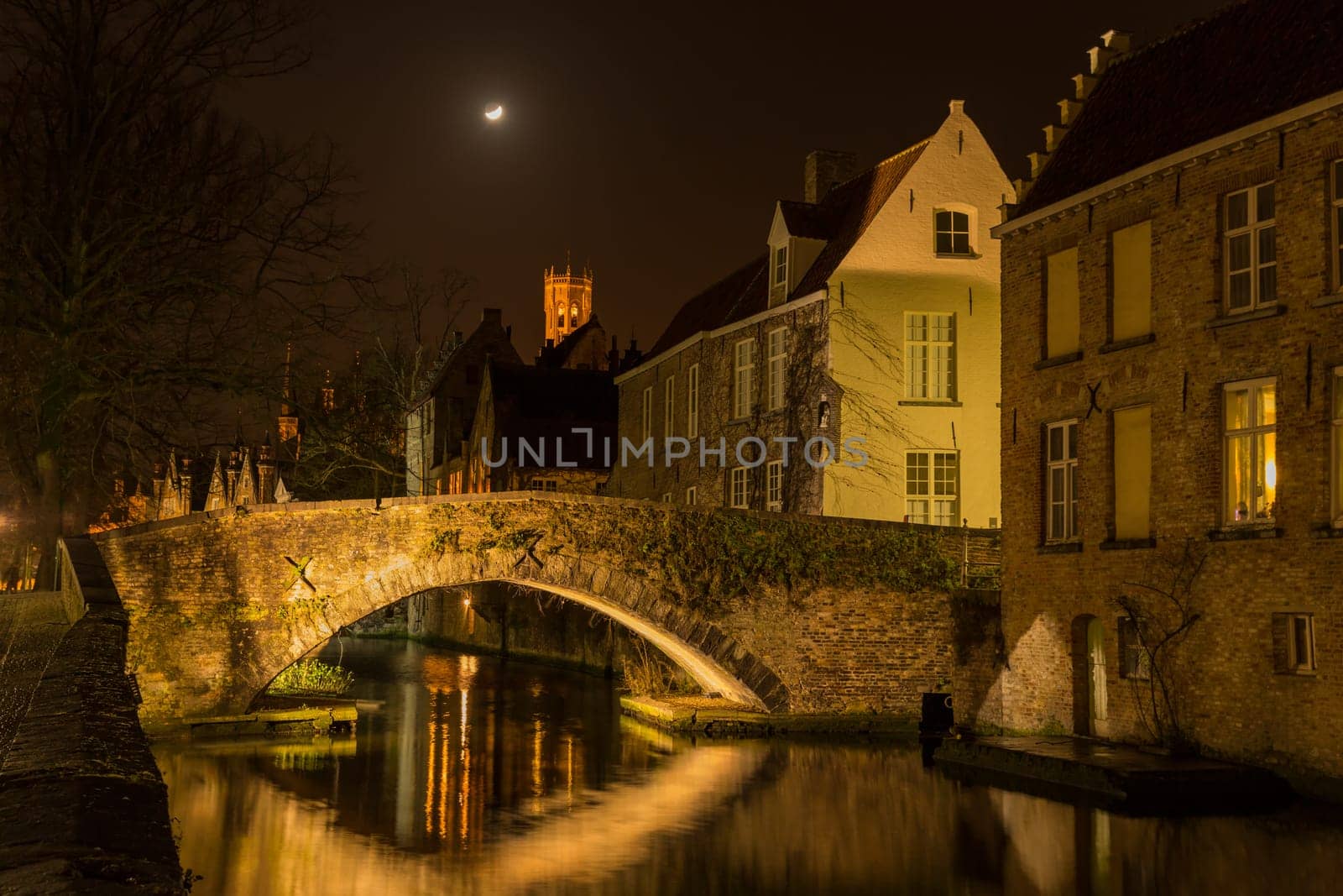 A canal in Bruges at night with illuminated bridges
