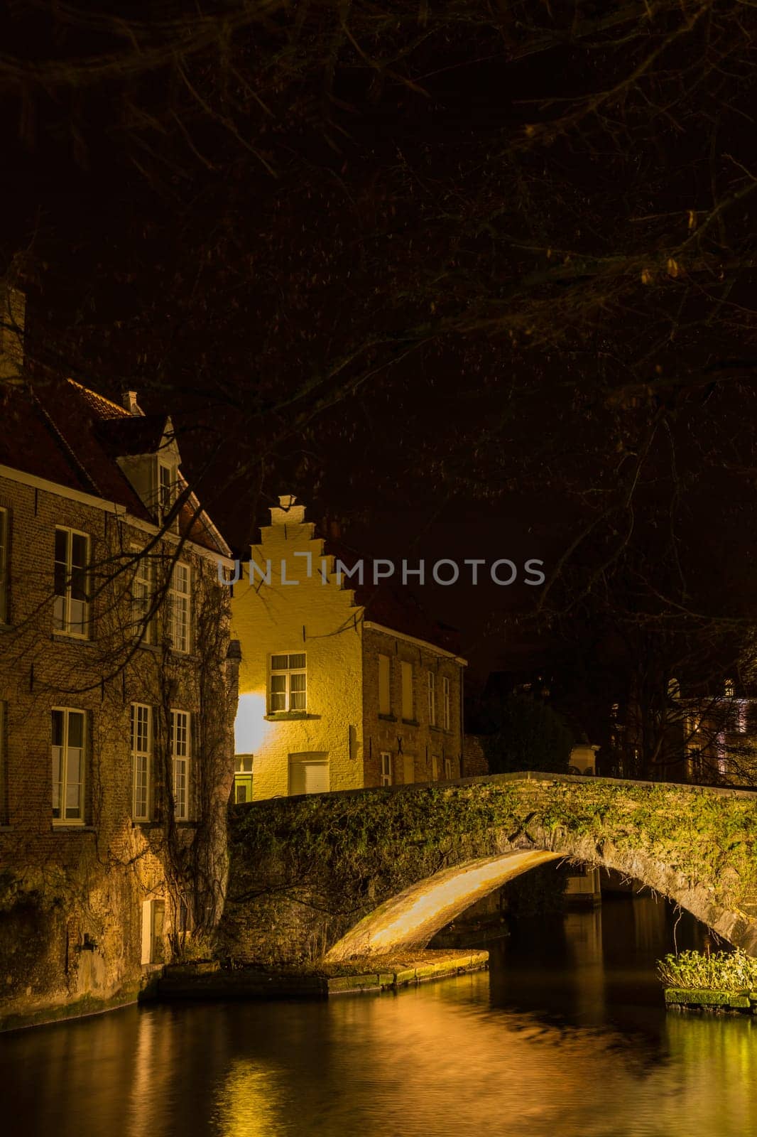 A canal in Bruges at night with illuminated bridges