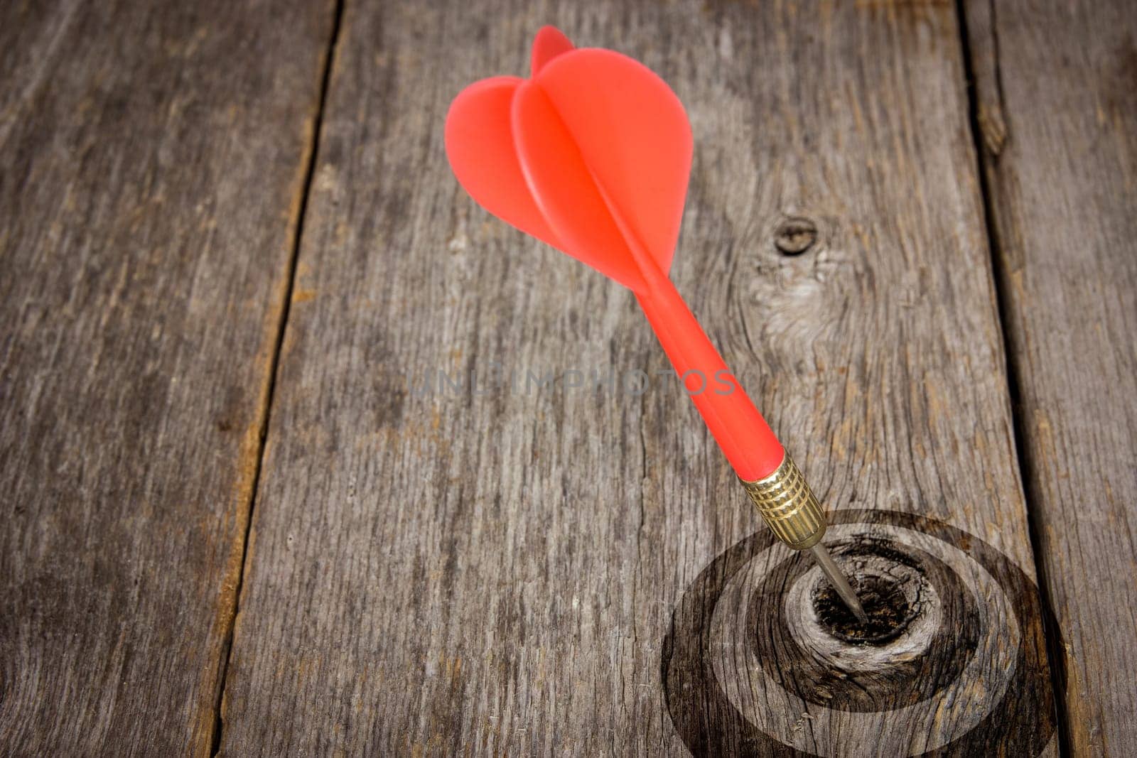Red dart hitting target on a wooden planks