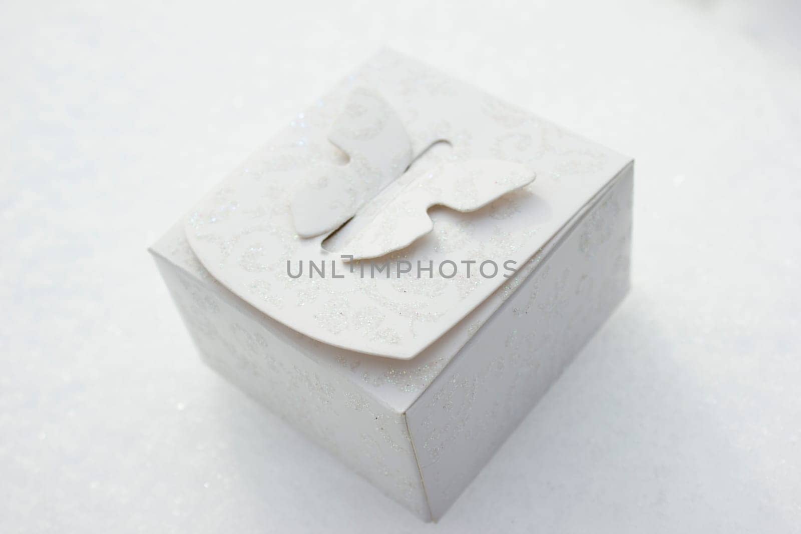 White gift box laying on a snow background.
