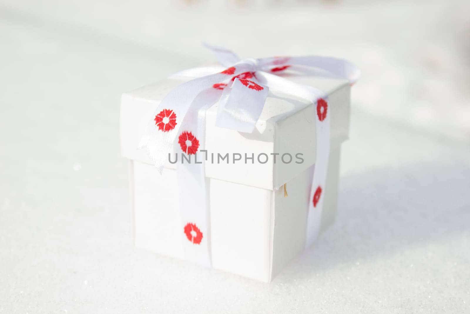 White gift box laying on a snow background.
