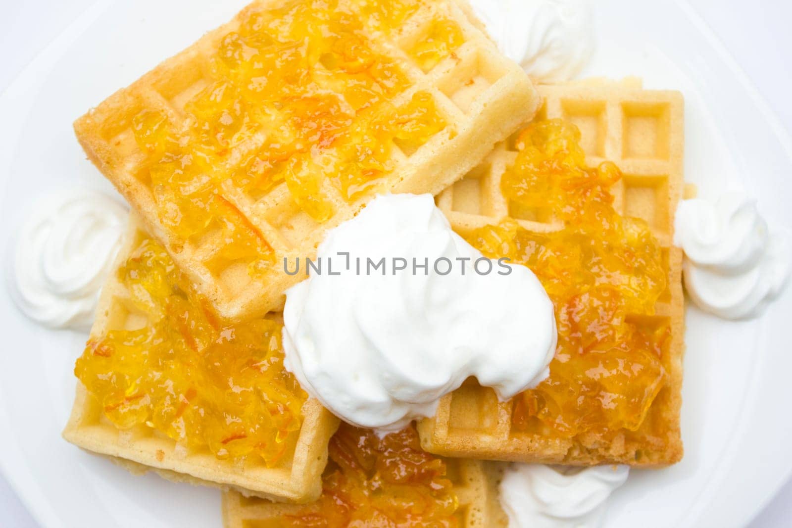 Toasted waffles with orange jam and cream on top.