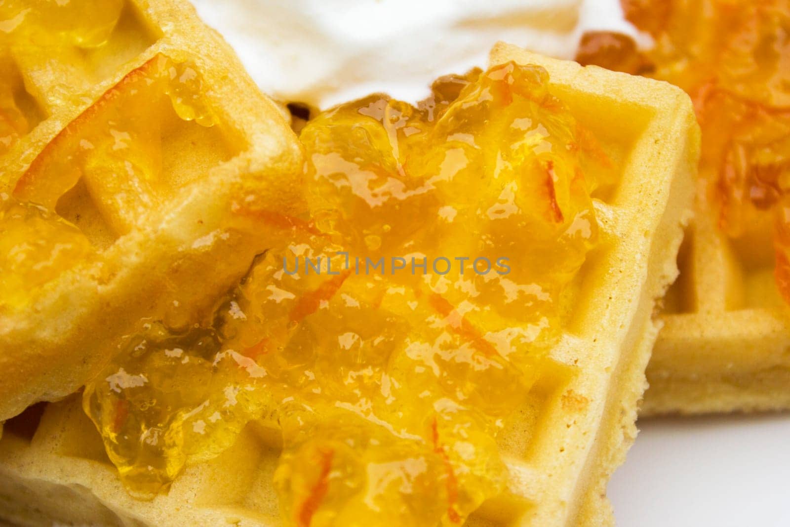 Toasted waffles with orange jam and cream on top.