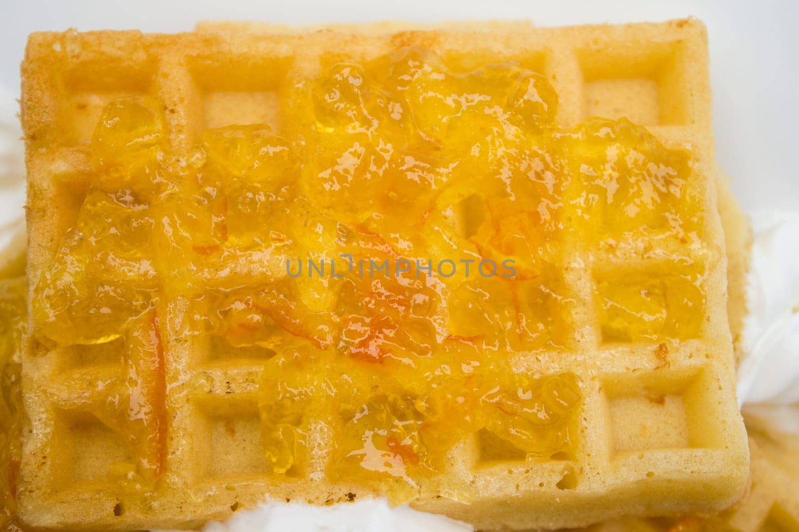 Toasted waffles with orange jam and cream on top.