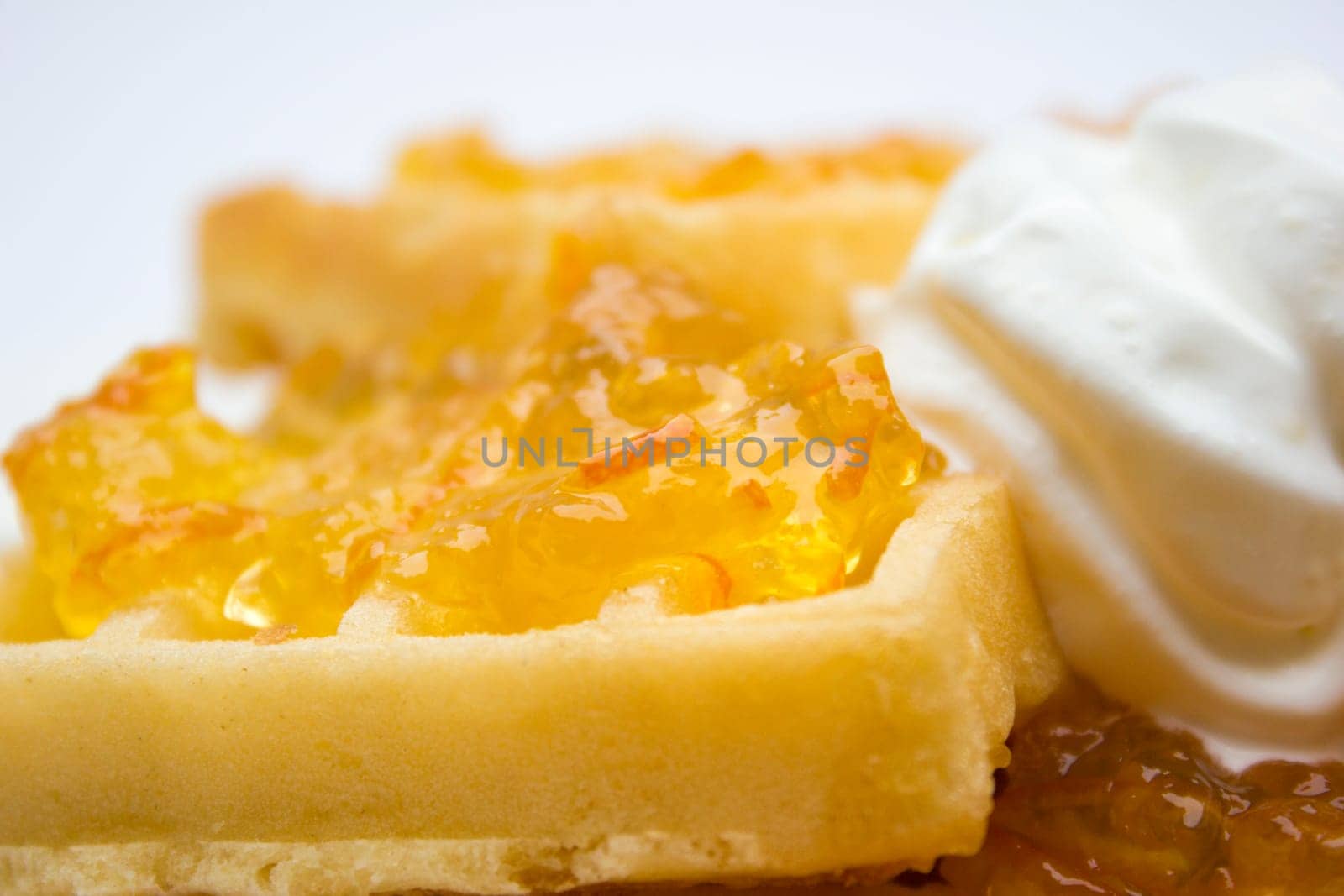 Toasted waffles with orange jam and cream on top.