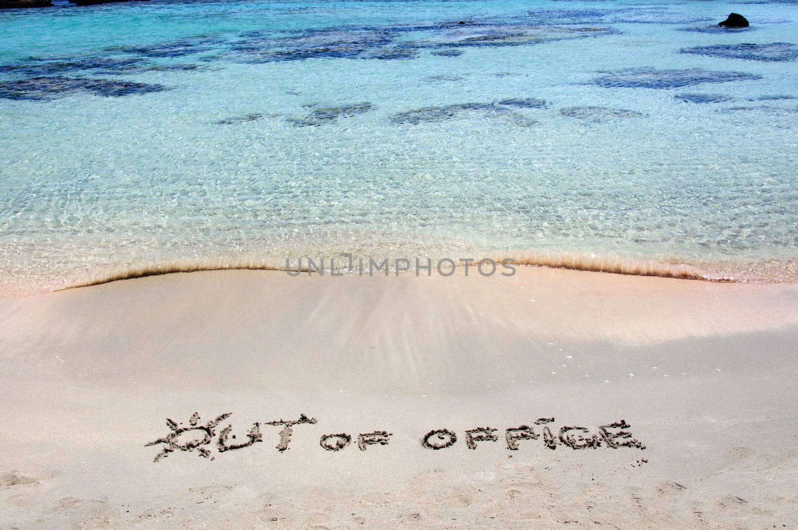 OUT OF OFFICE written on sand on a beautiful beach, blue waves in background .Relax concept image