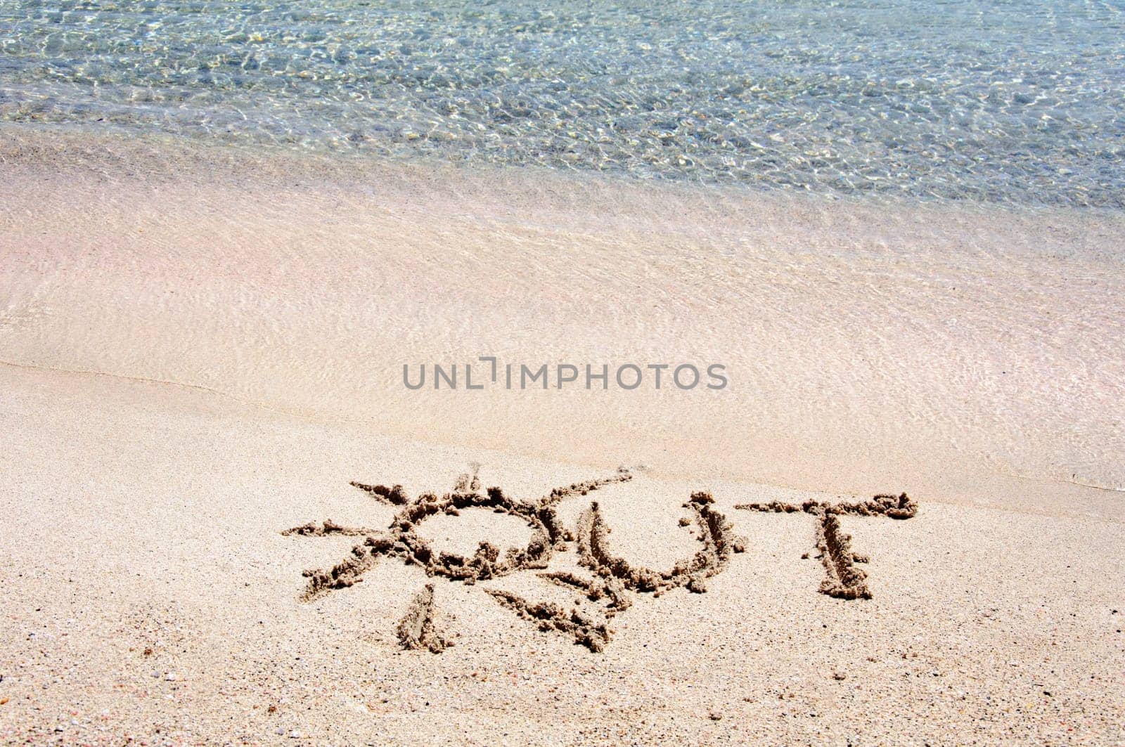 Word "OUT"" written on sand on a beautiful beach, blue waves in background"