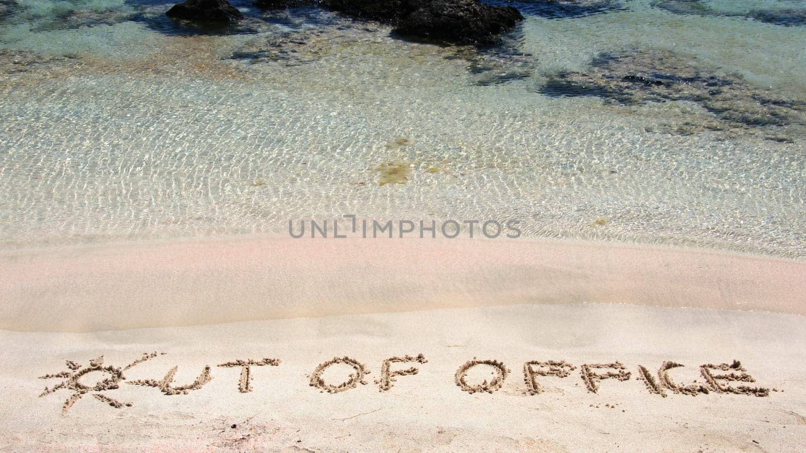 OUT OF OFFICE written on sand on a beautiful beach, blue waves in background .Relax concept image