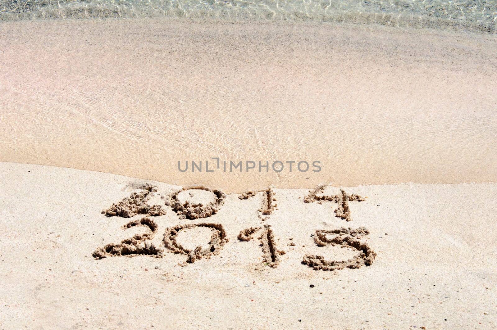 New Year 2015 is coming concept - inscription 2014 and 2015 on a beach sand, the wave is starting to cover the digits 2014