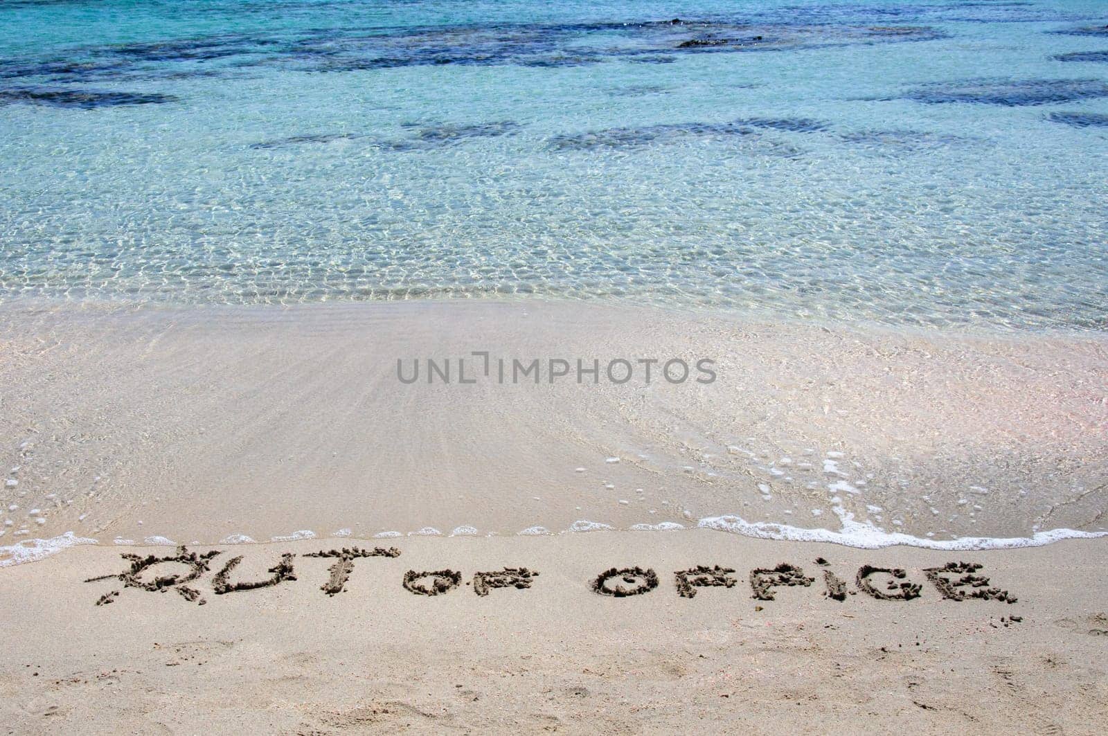 OUT OF OFFICE written on sand on a beautiful beach, blue waves in background .Relax concept image