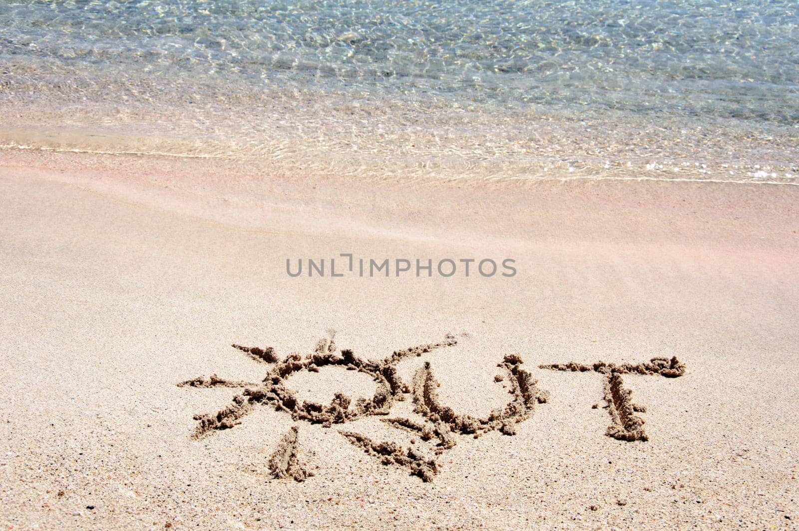 Word "OUT"" written on sand on a beautiful beach, blue waves in background"