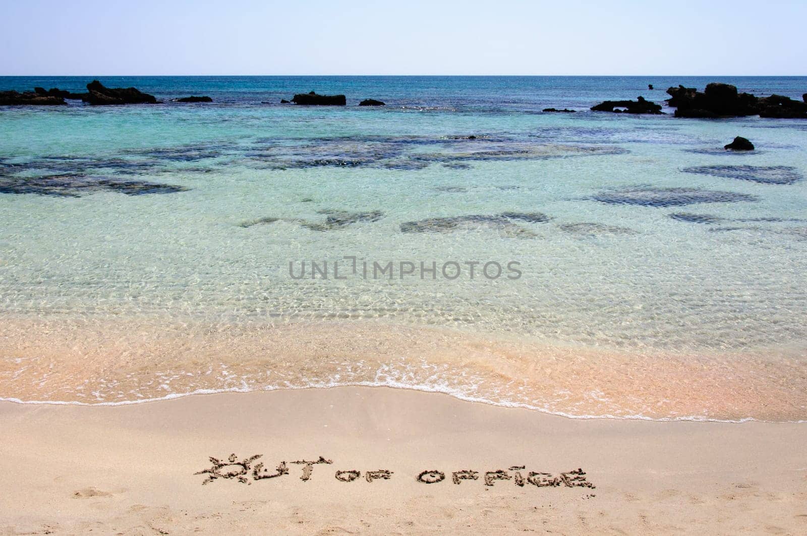 OUT OF OFFICE written on sand on a beautiful beach, blue waves in background .Relax concept image