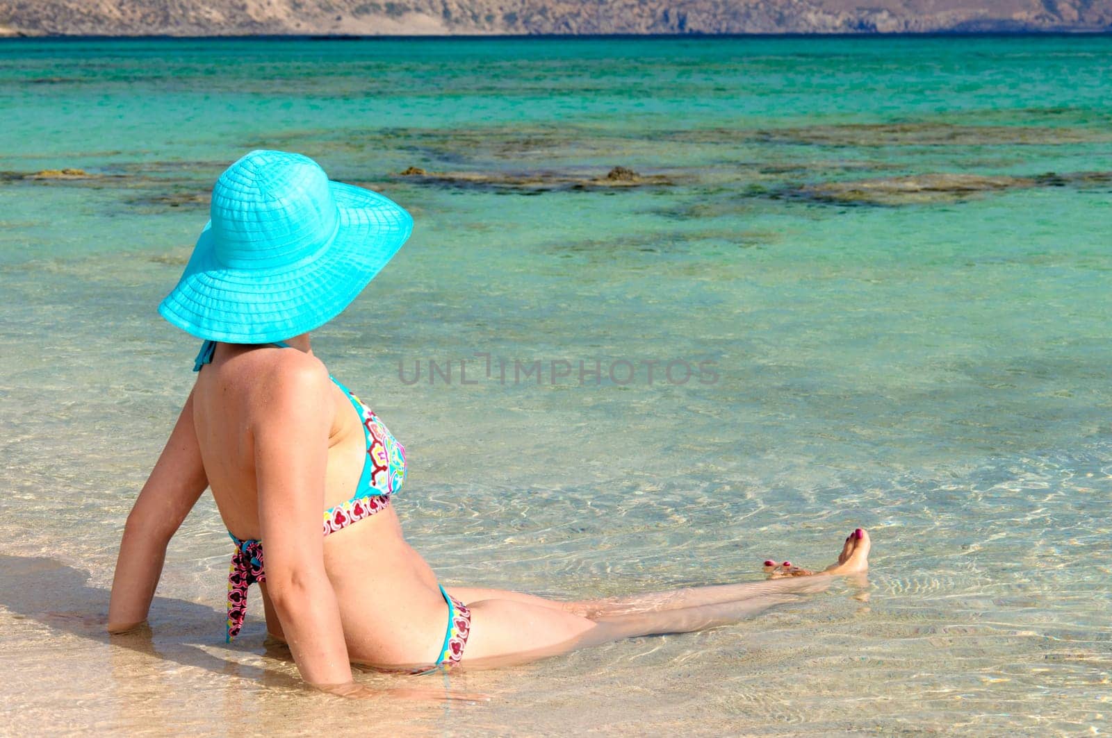 Beautiful young woman in bikini with sunhat, relaxing on the sunny beach. Relaxing concept
