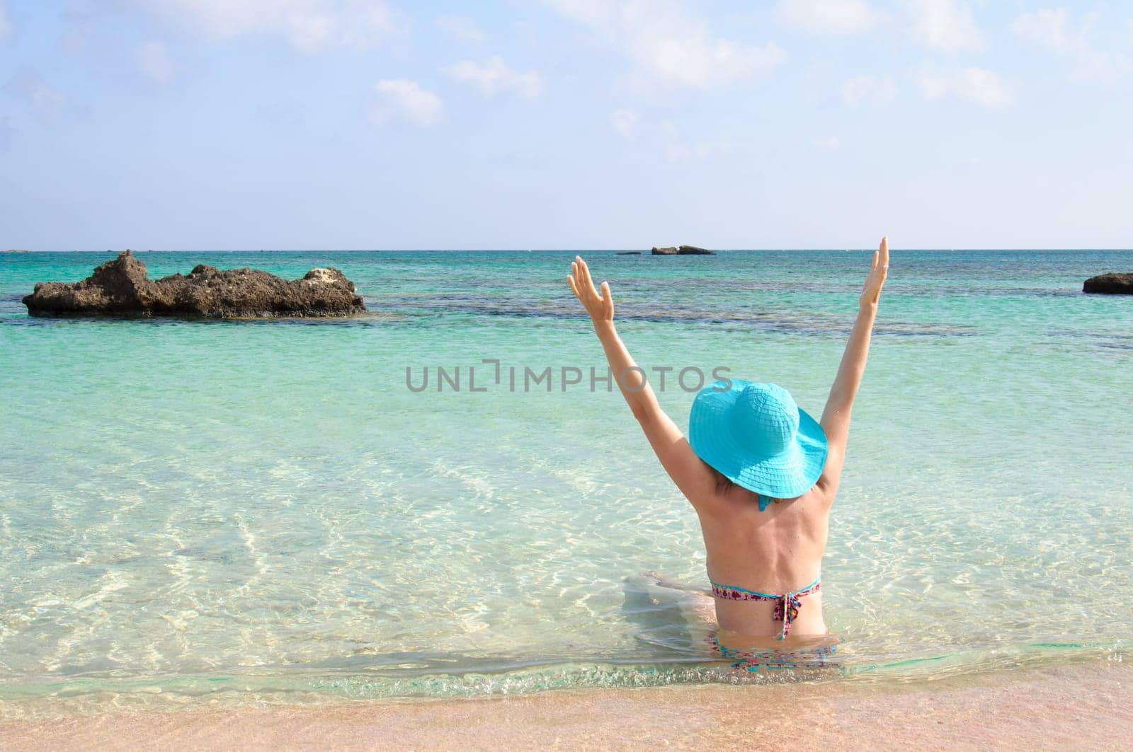 Beautiful young woman in bikini with sunhat, relaxing on the sunny beach. Relaxing concept