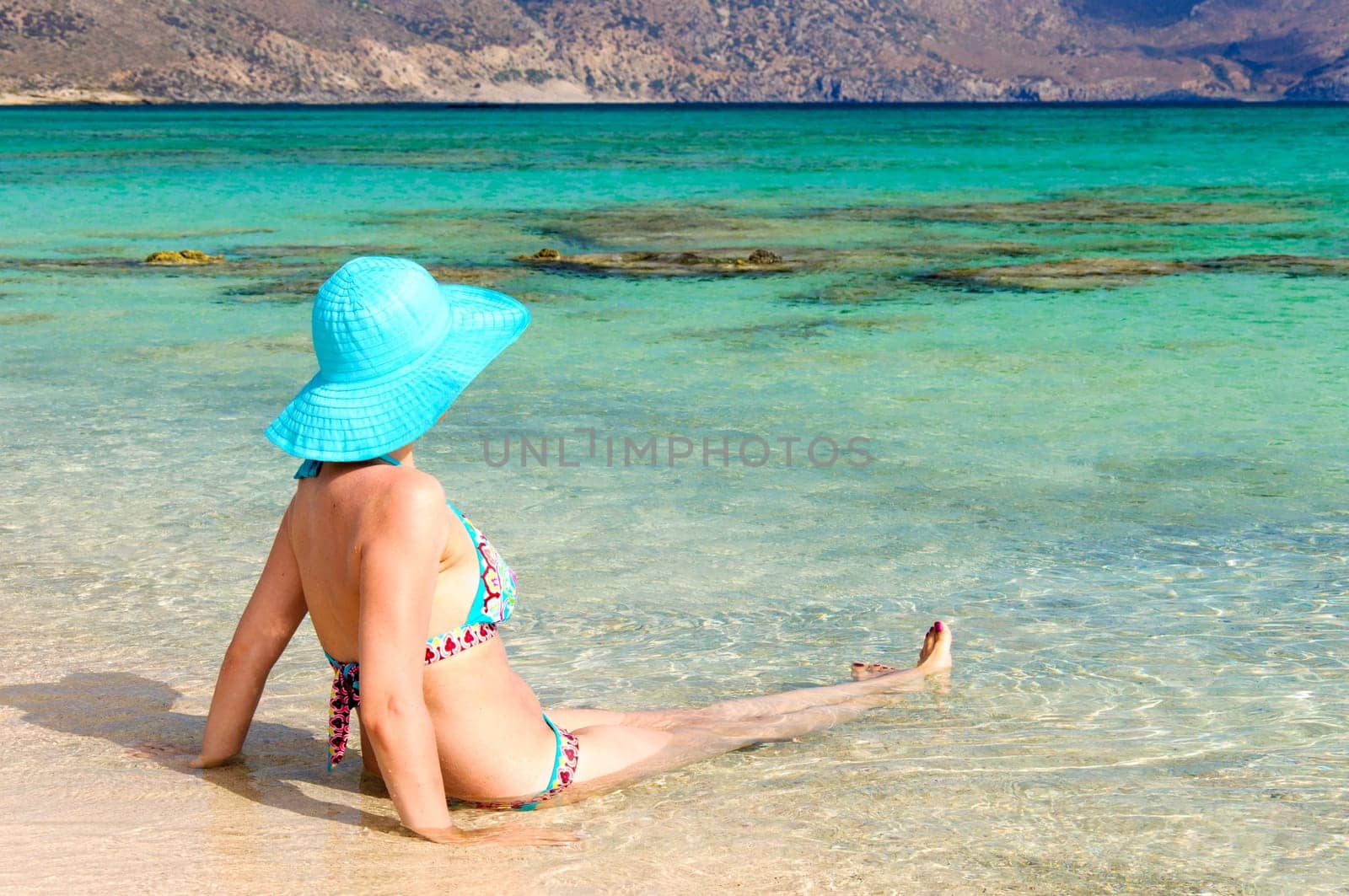 Beautiful young woman in bikini with sunhat, relaxing on the sunny beach. Relaxing concept