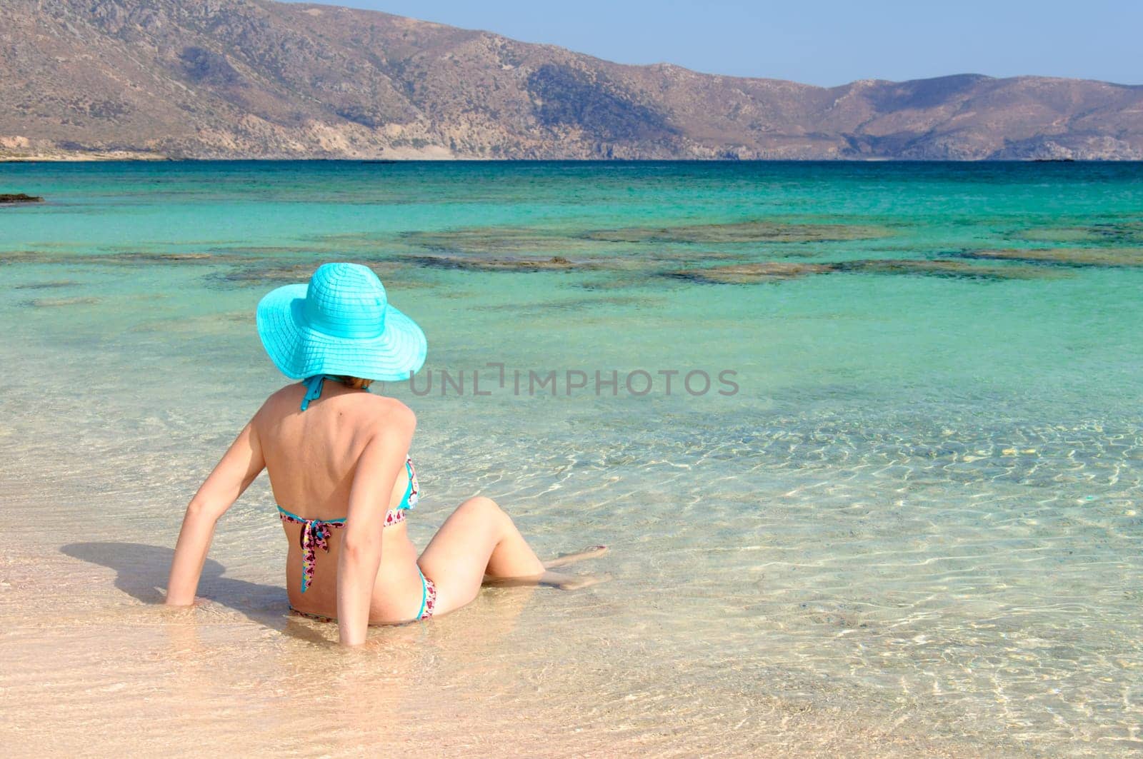 Beautiful young woman in bikini with sunhat, relaxing on the sunny beach. Relaxing concept