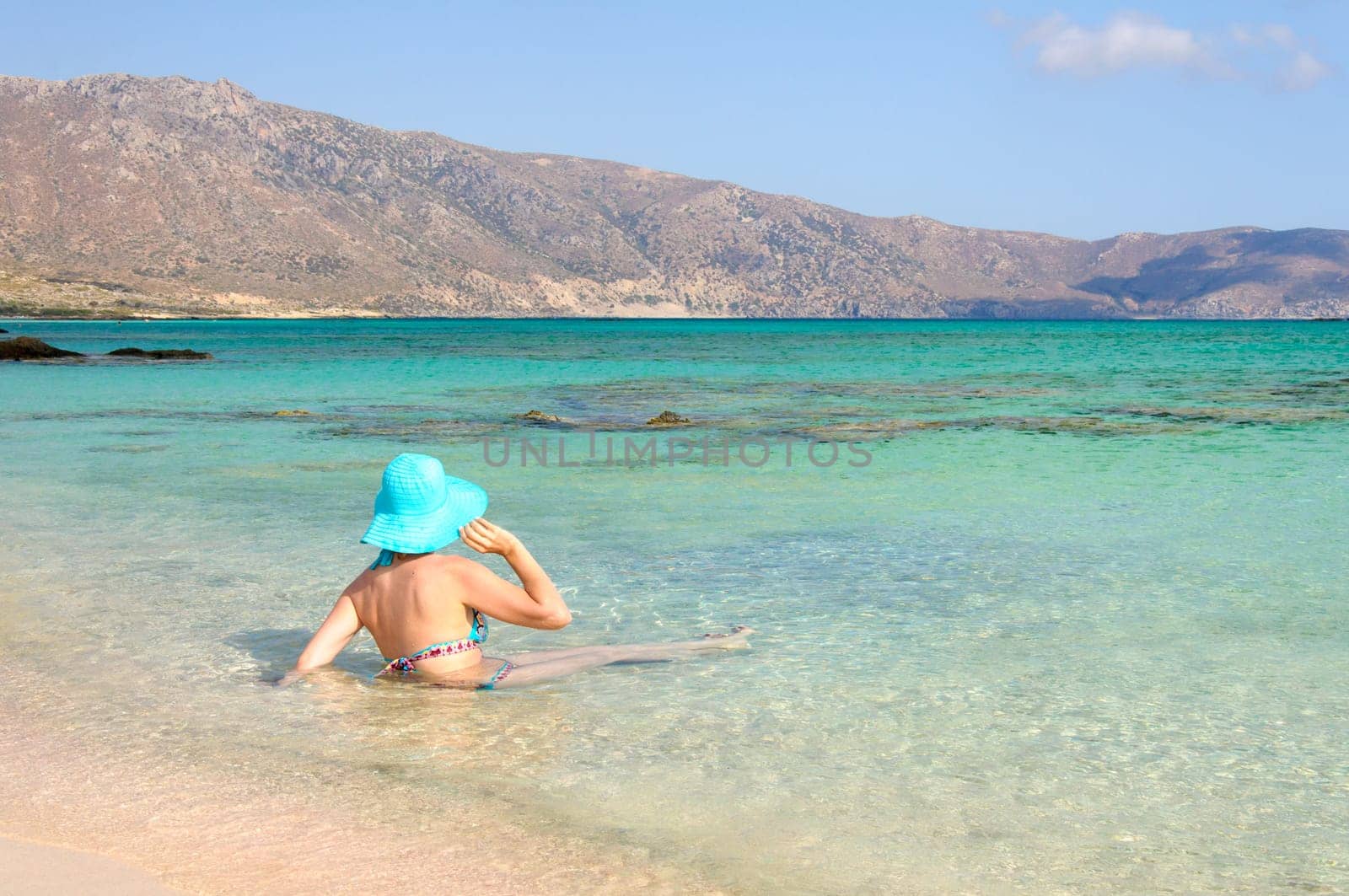 Beautiful young woman in bikini with sunhat, relaxing on the sunny beach. Relaxing concept