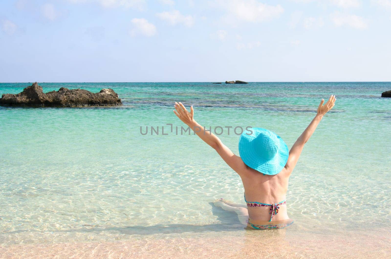 Beautiful young woman in bikini with sunhat, relaxing on the sunny beach. Relaxing concept