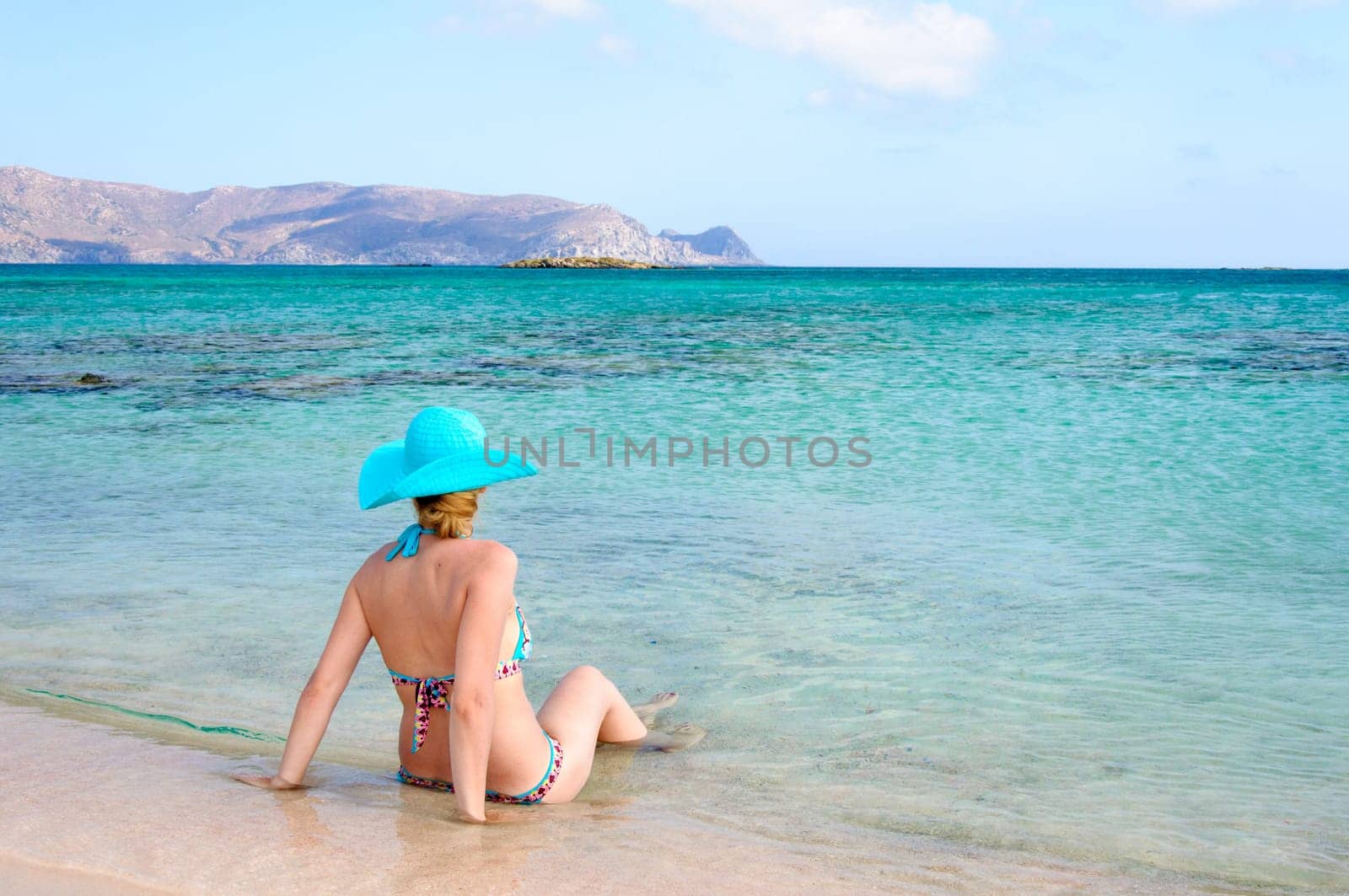 Beautiful young woman in bikini with sunhat, relaxing on the sunny beach. Relaxing concept