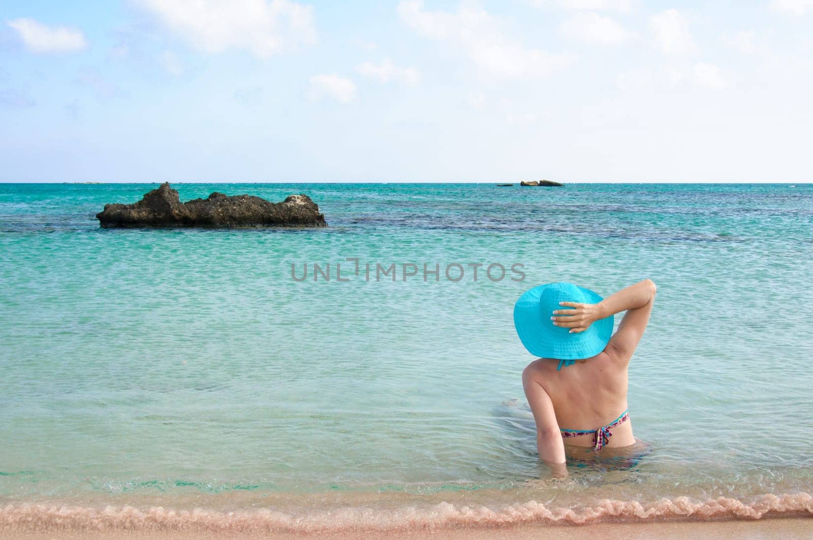 Beautiful young woman in bikini with sunhat, relaxing on the sunny beach. Relaxing concept