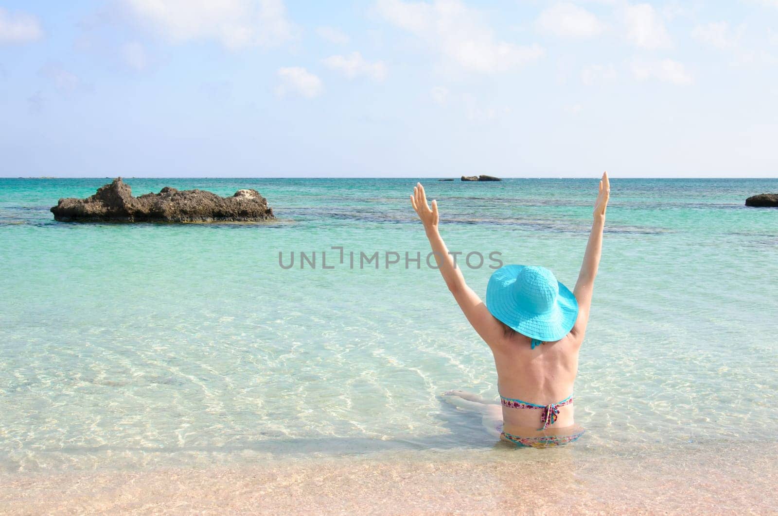 Beautiful young woman in bikini with sunhat, relaxing on the sunny beach. Relaxing concept
