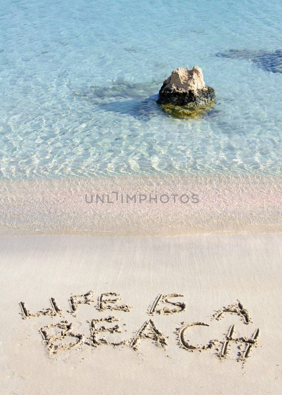 Life is a beach message written on white sand, with tropical sea waves in background
