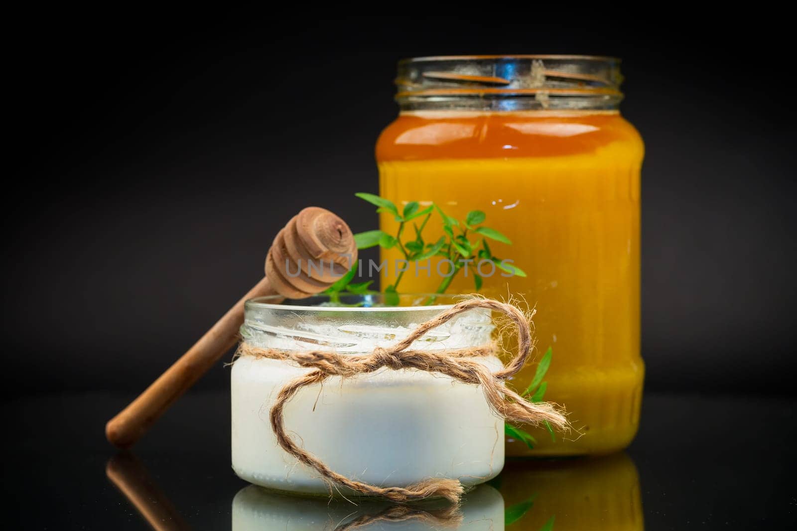 jar with natural homemade yogurt and delicious organic honey, isolated on a black background.