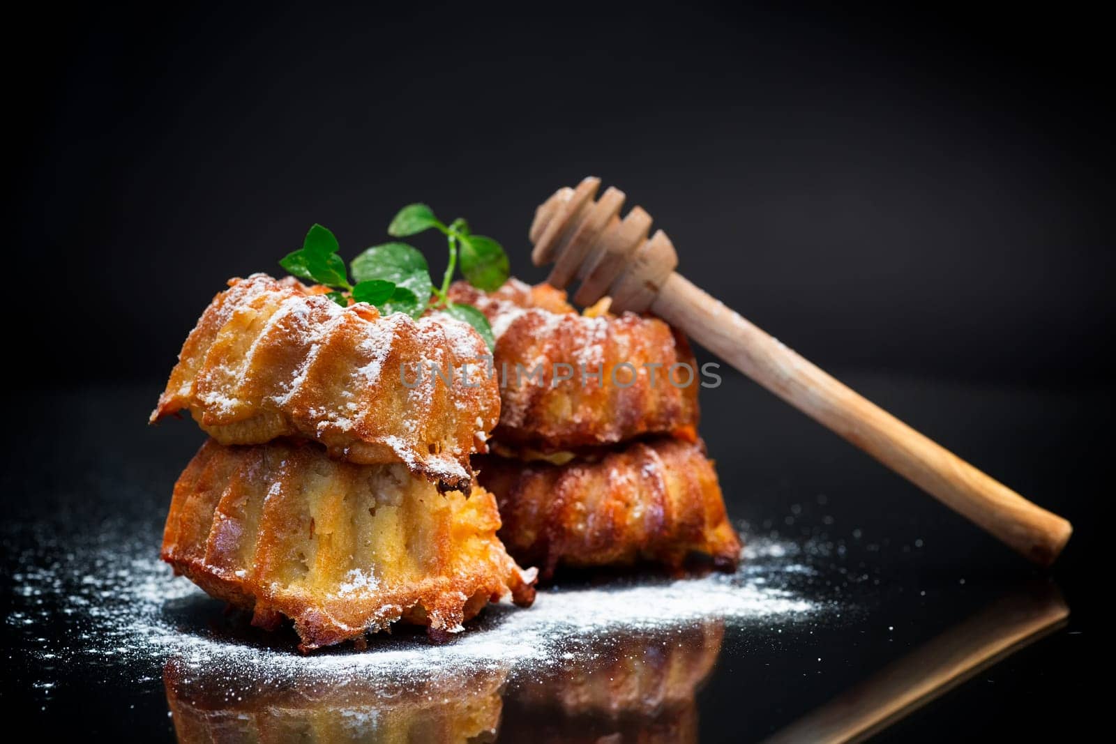 cooked sweet honey muffins in powdered sugar isolated on black background