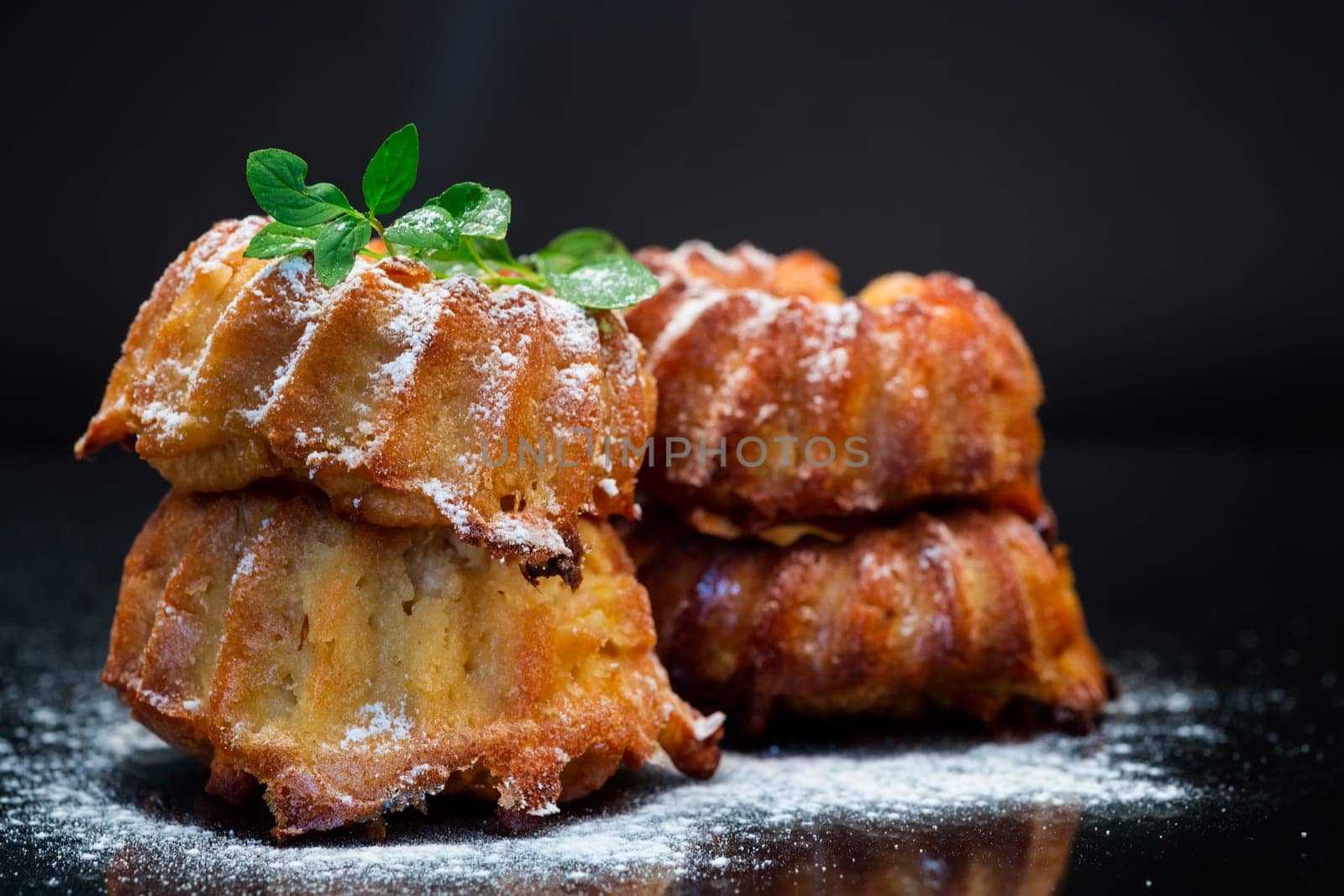 cooked sweet honey muffins in powdered sugar isolated on black background