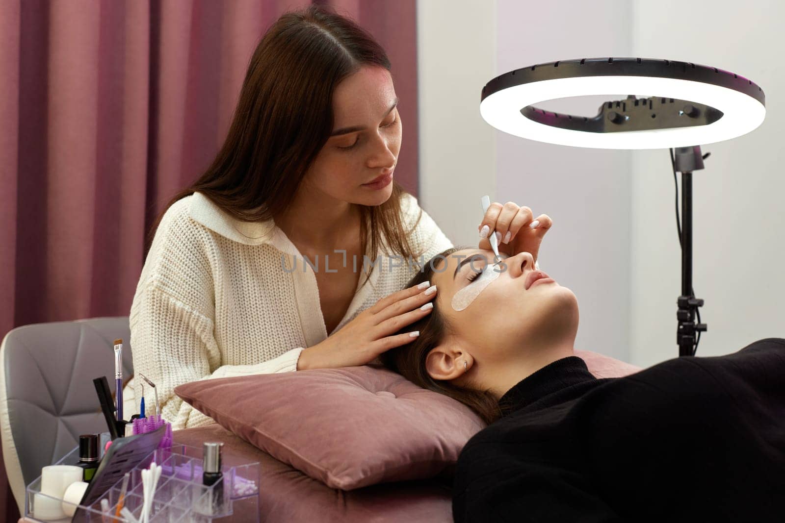 cosmetologist removes glue cotton tape under eye. Eyelash extension procedure