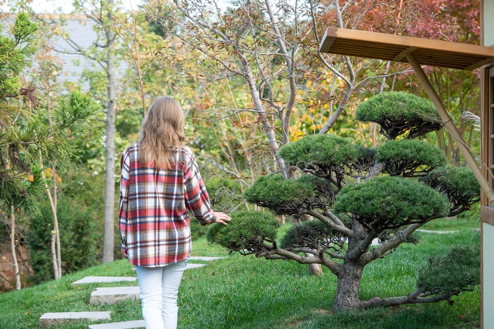 back view of Woman in red plaid shirt enjoying nature walking in Japanese Garden