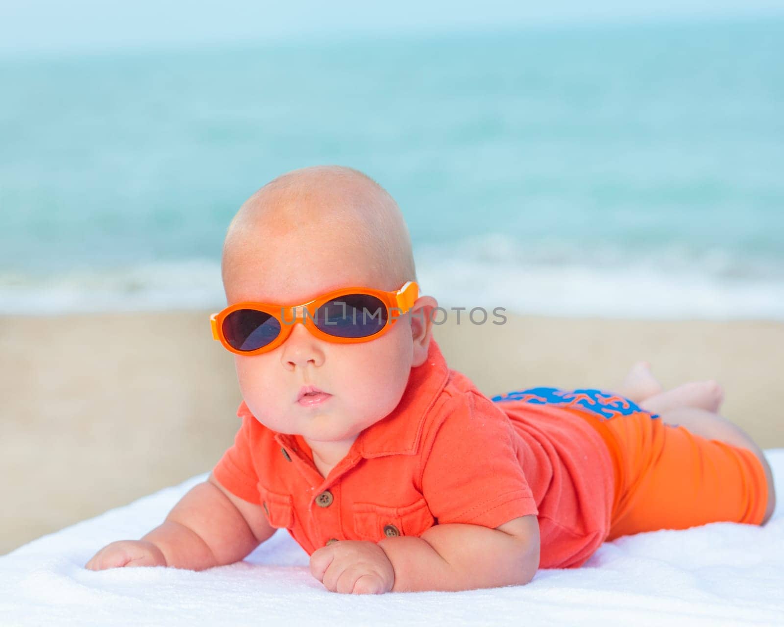 Cute baby wearing sunglasses on the sunbed