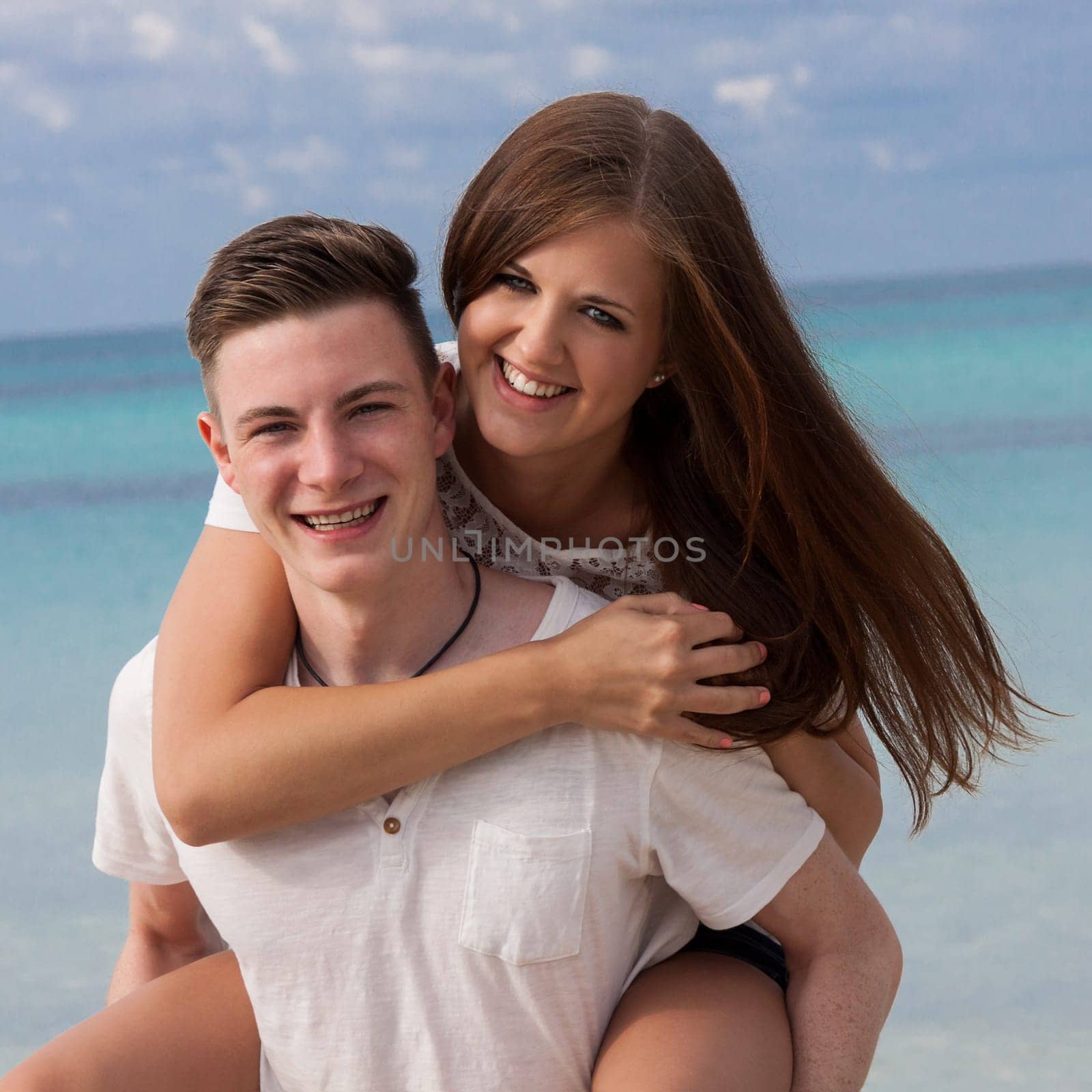 Laughing young couple in love happy on the beach in summer leisure holiday