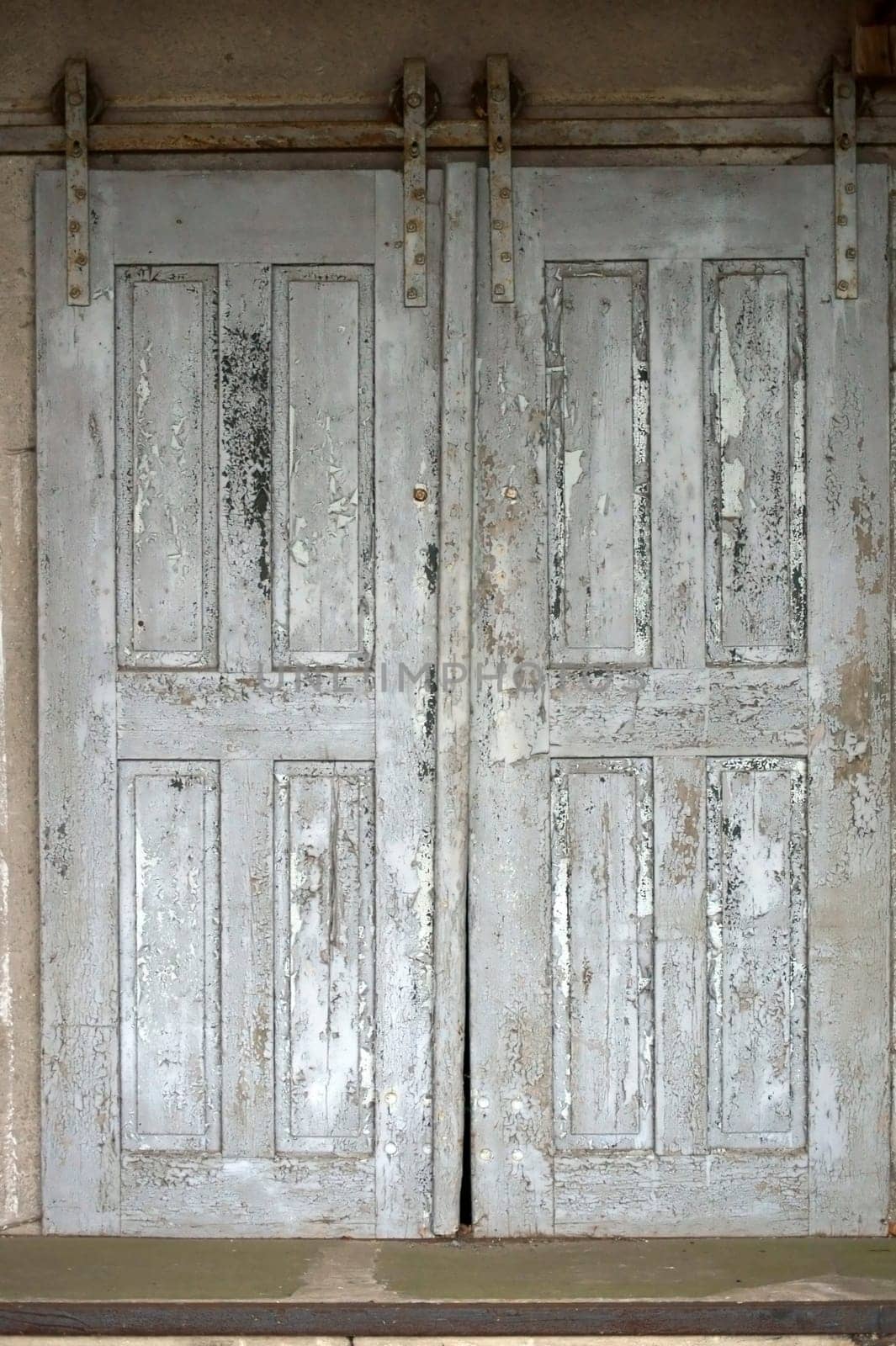 The photograph of an old sliding door of the ruins of a farm and storage building.