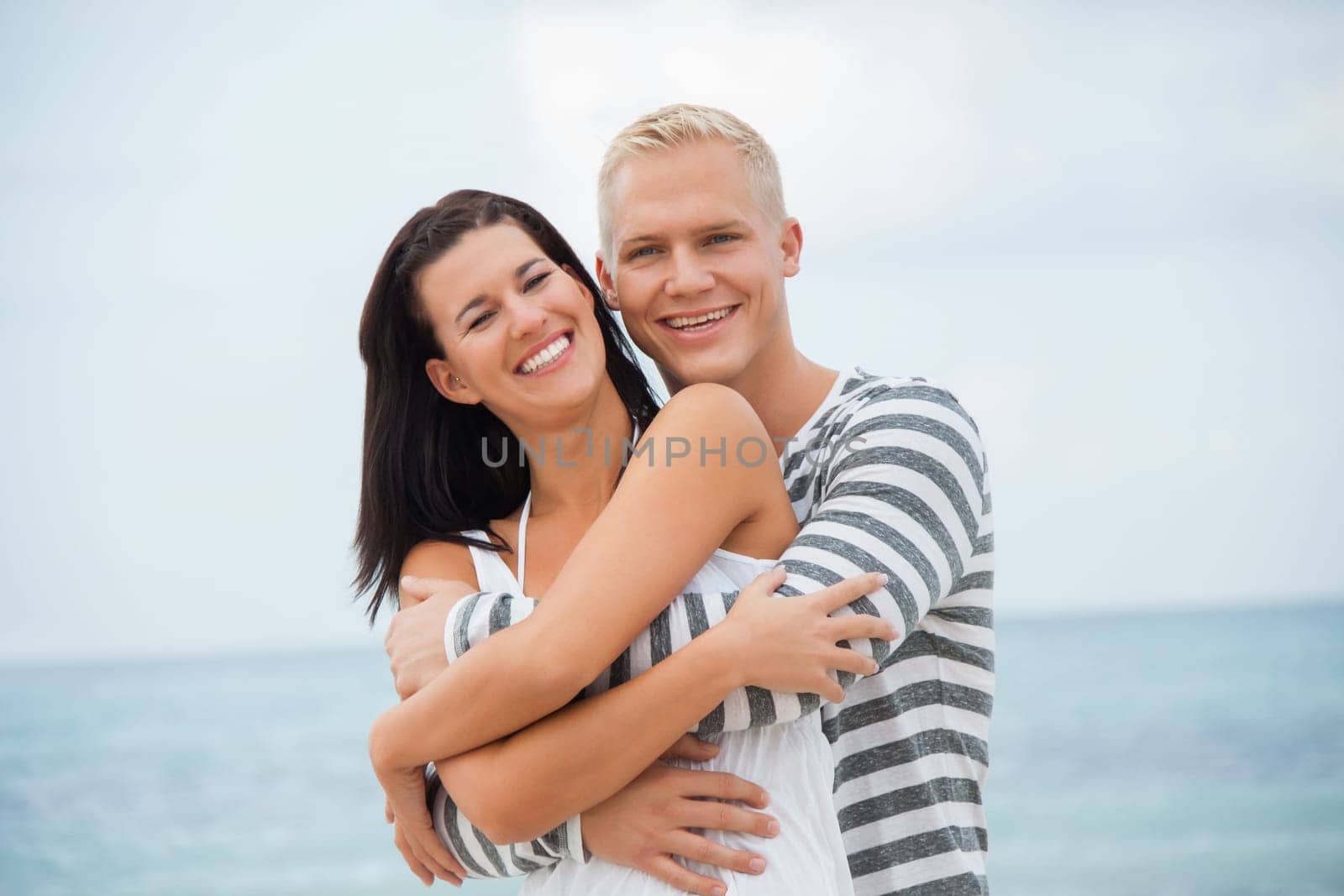 Young happy couple in love has fun on the beach in summer