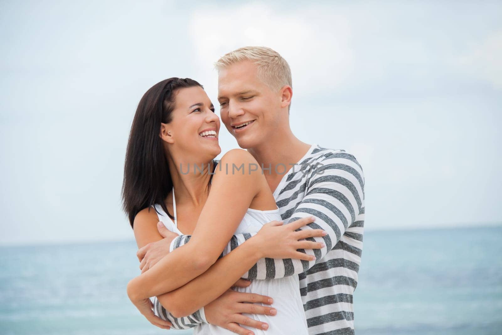 Young happy couple in love has fun on the beach in summer