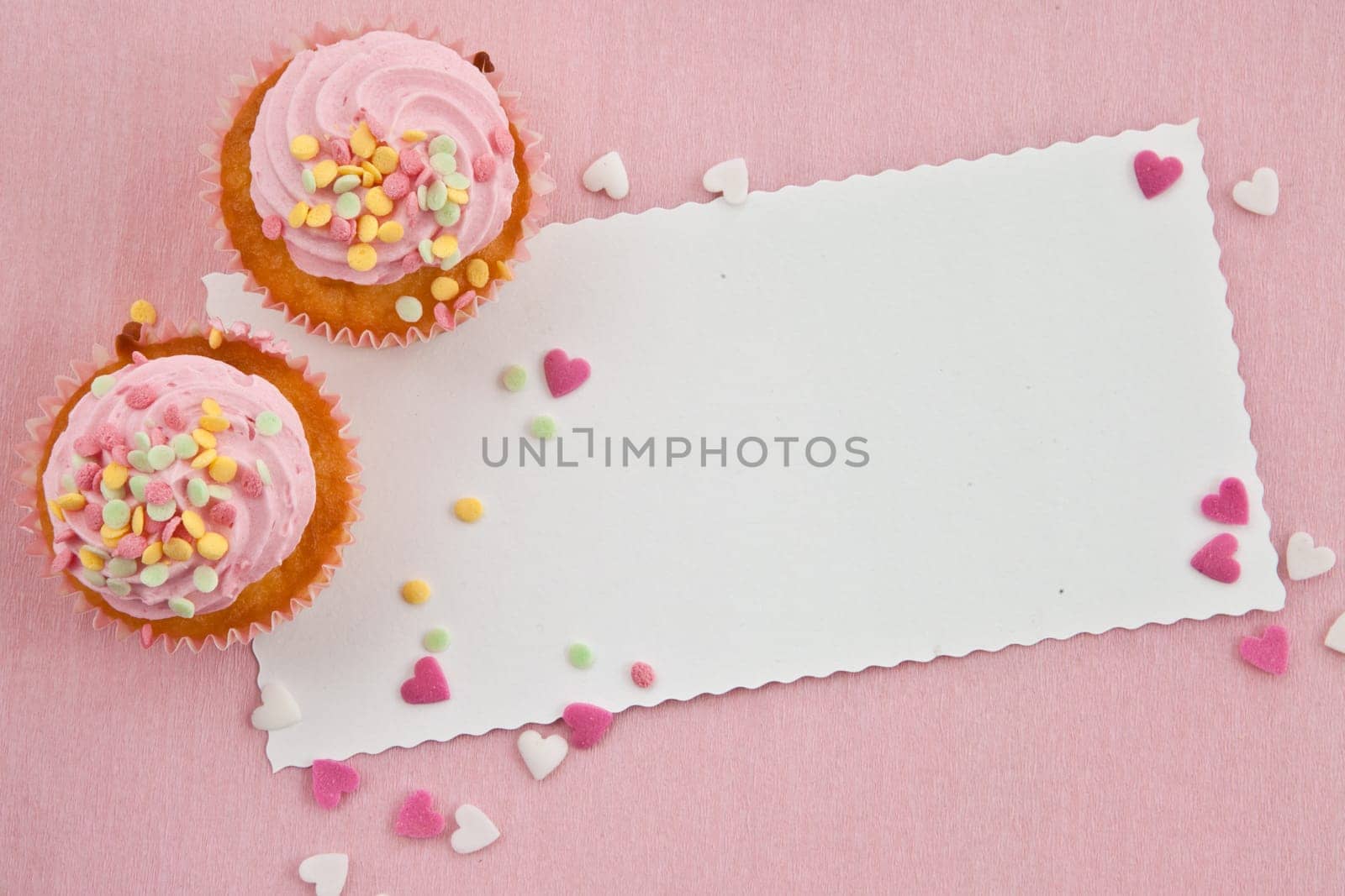 Small cupcake with colorful sugar sprinkles on pink