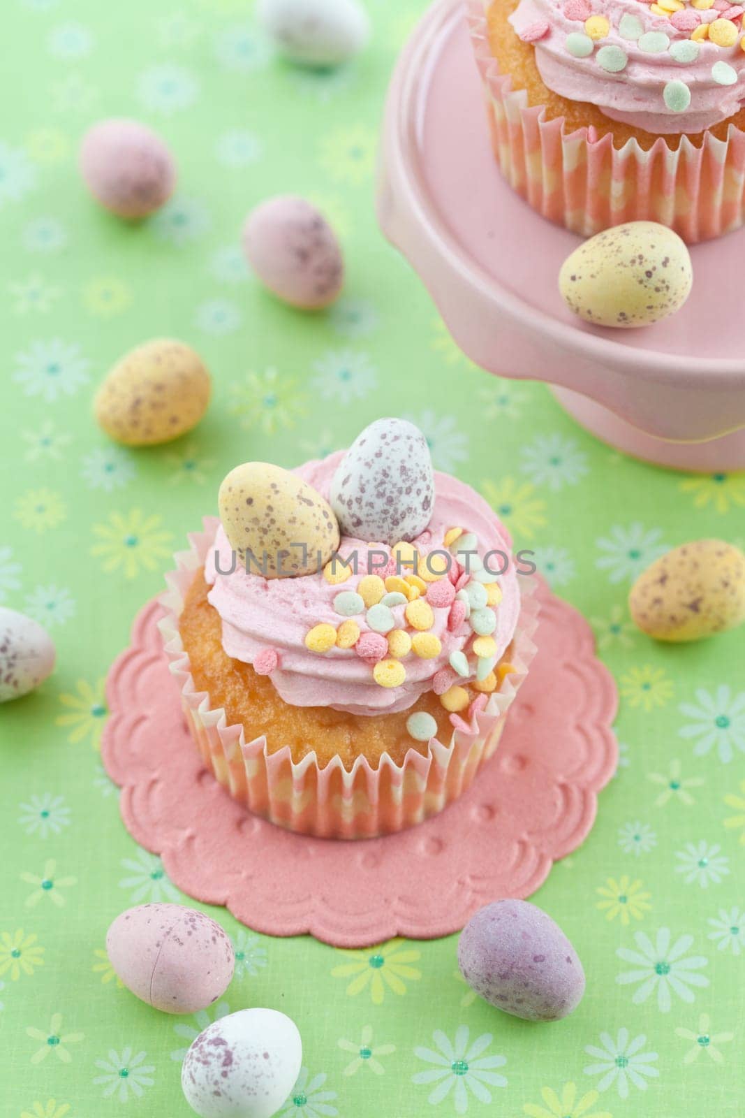 Small colorful cupcake with Easter eggs on a green background