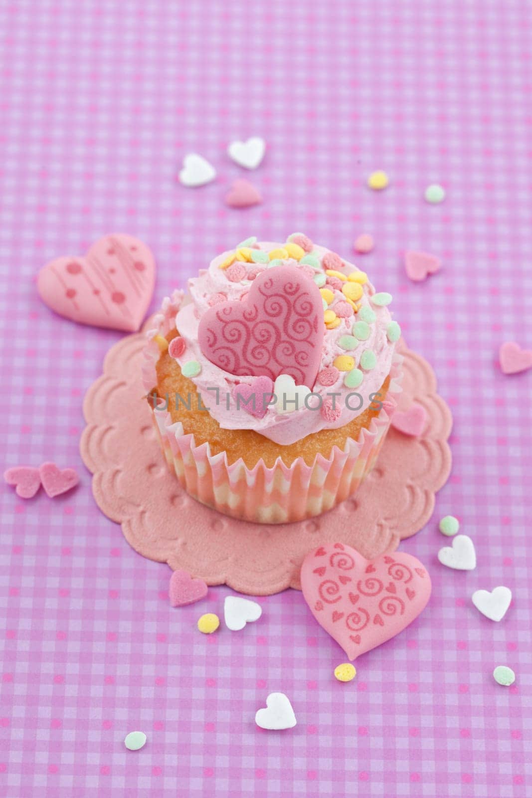 Small cupcake with colorful hearts on purple background